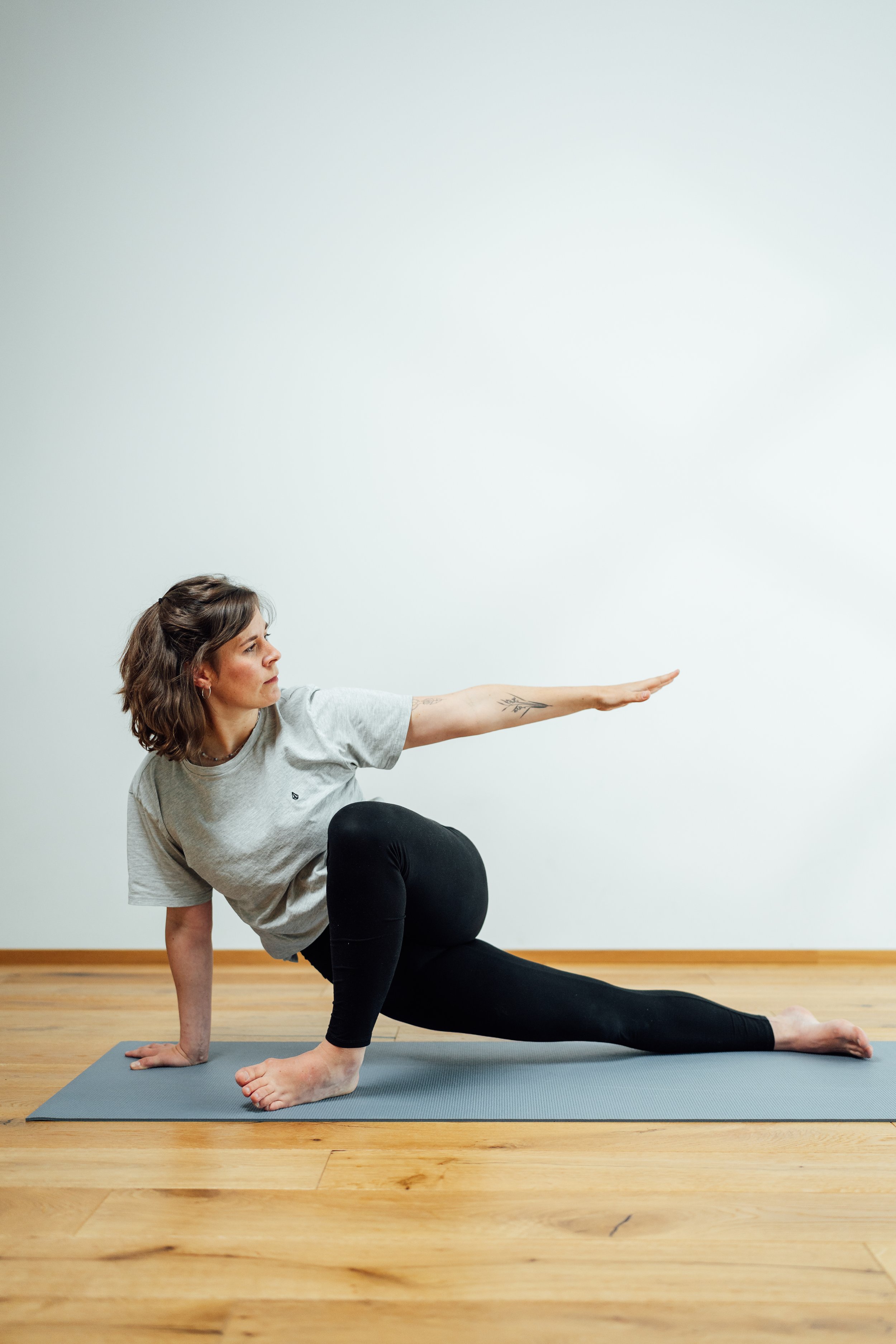 Frau macht Yoga auf einer Matte,Balance in der Haltung, helle Wand im Hintergrund.