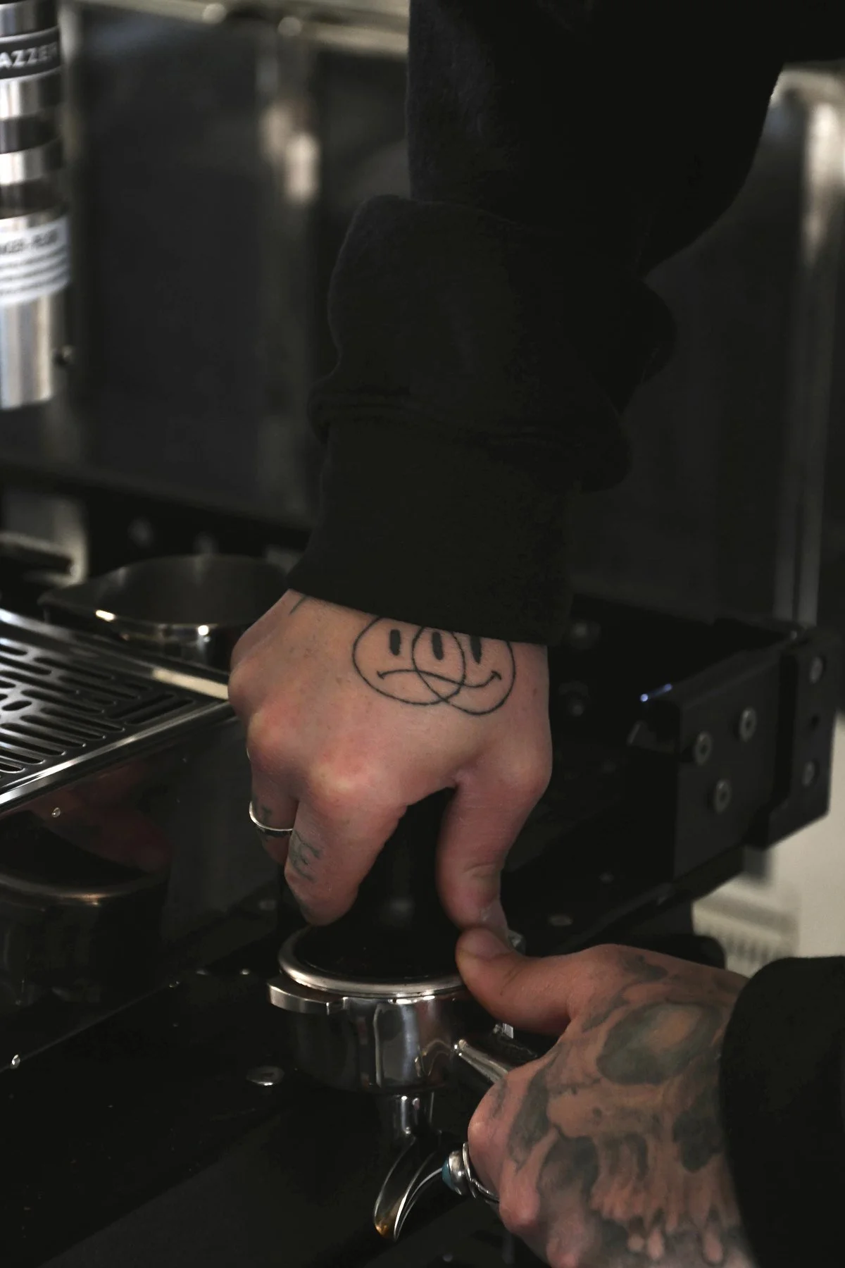 Street Coffee Collective barista tamping espresso, tattooed hand