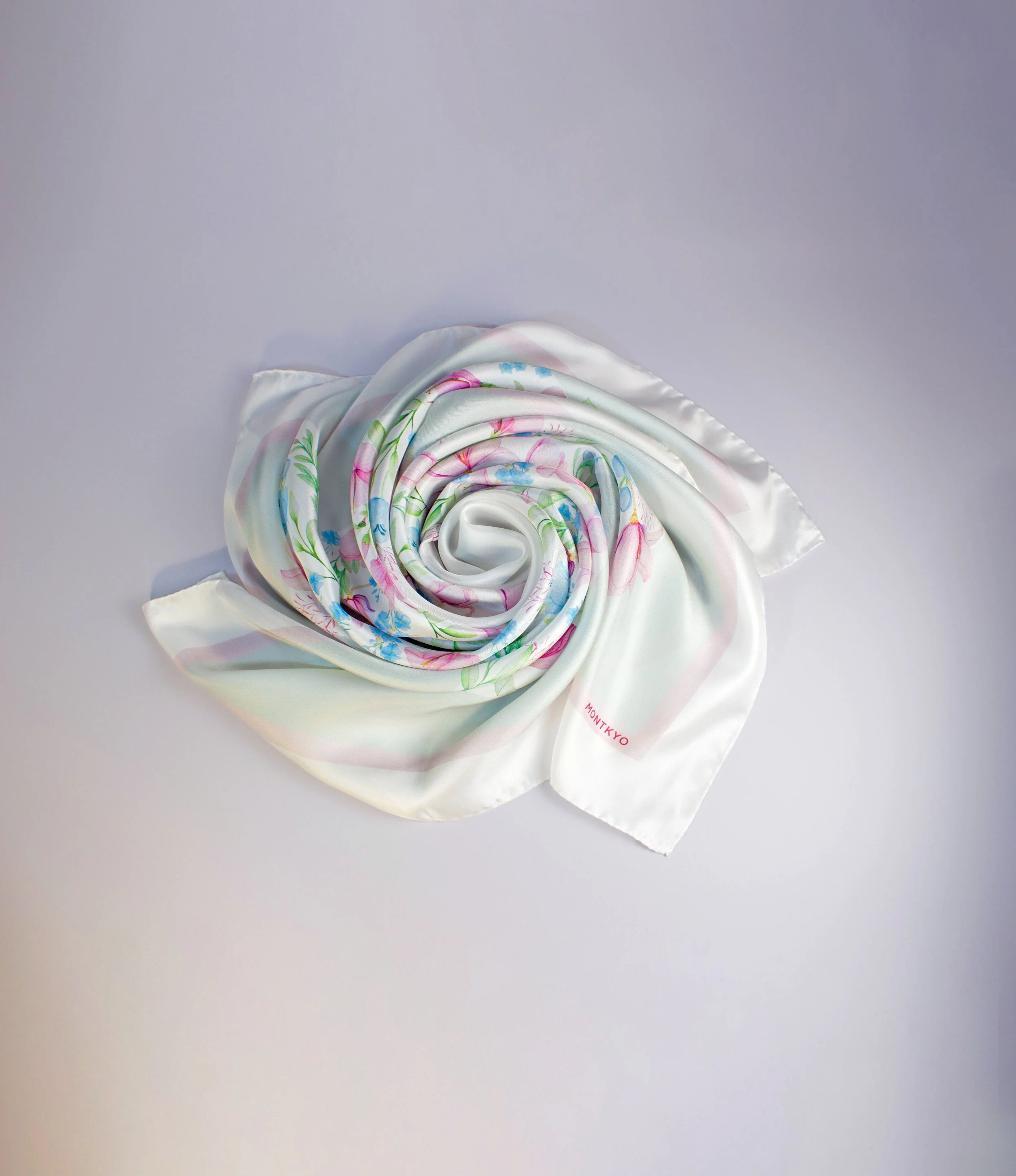 Quiet Garden silk scarf by MONTKYO twisted and arranged on a tabletop, showing the water-color illustrated pattern.