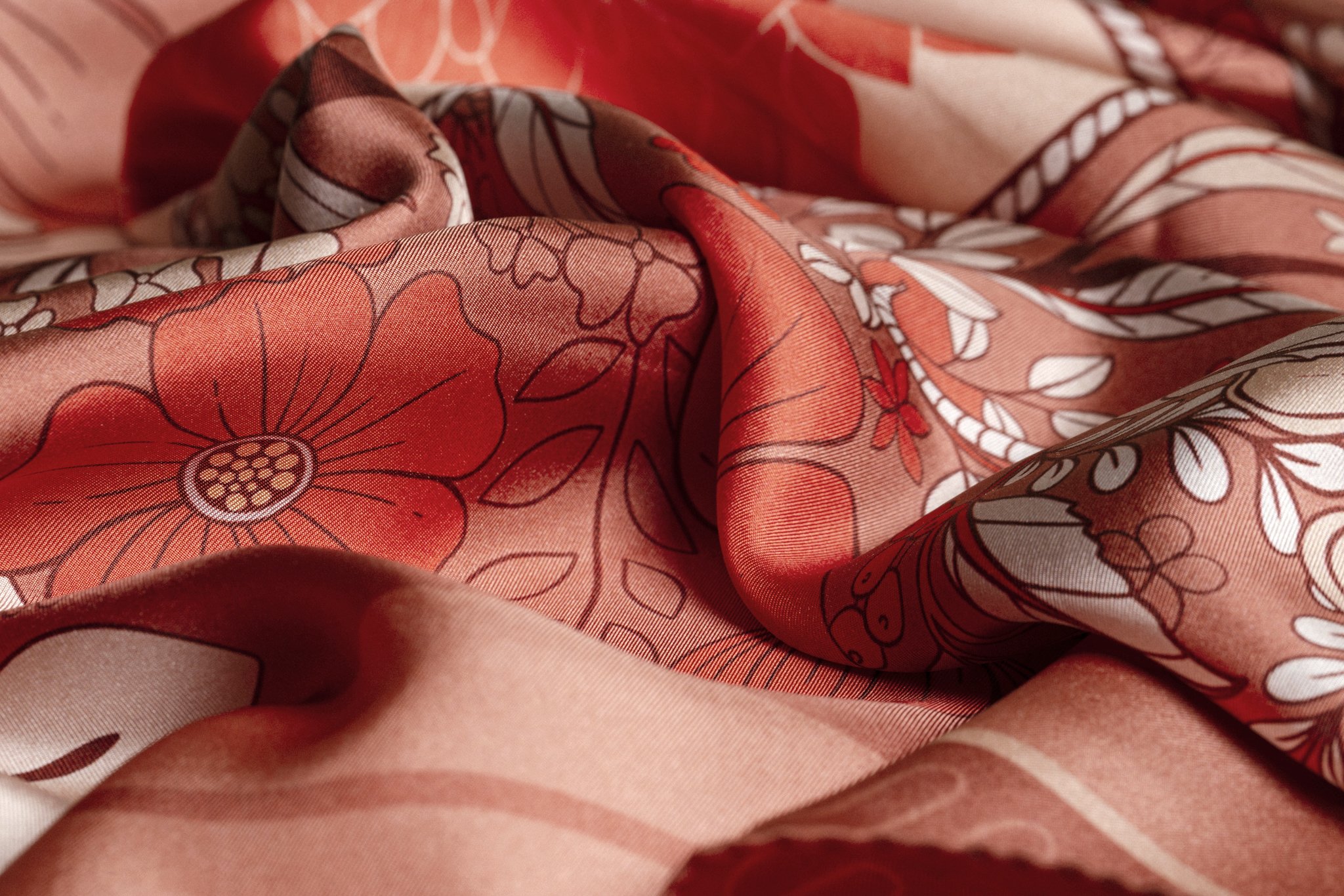 Close-up of the Wild Bloom hand-illustrated silk scarf by MONTKYO, showing detailed flowers and leaves in muted reddish tones.