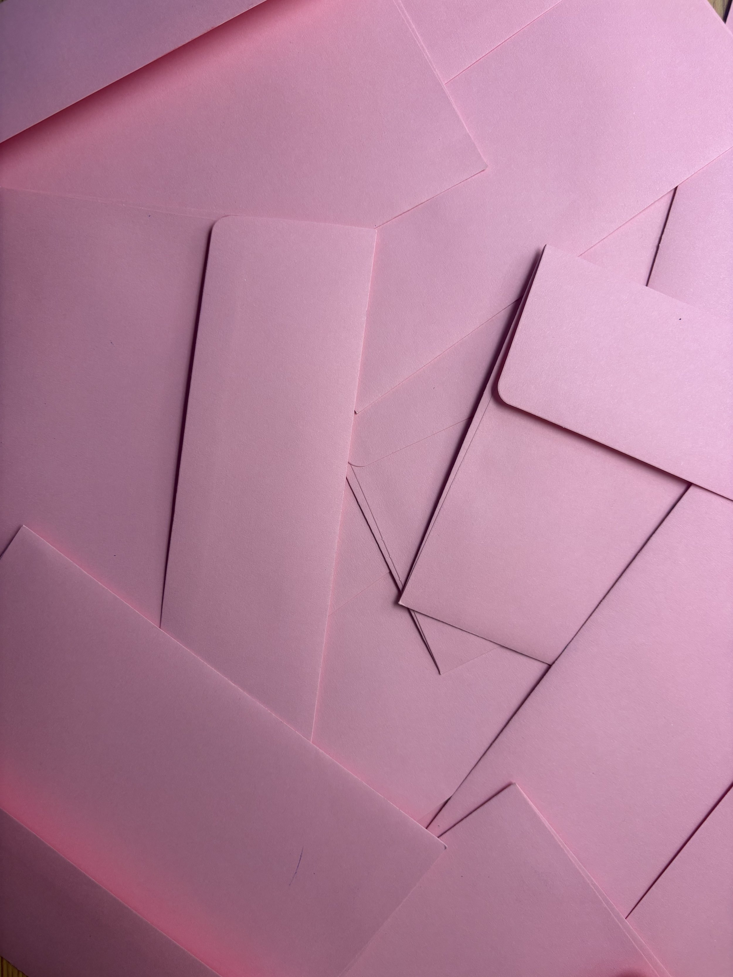 Multiple pink envelopes and cards arranged on a pink background.