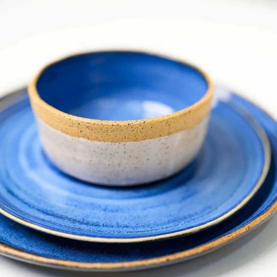 Stacked blue and white ceramic bowls and plates with a gold rim.