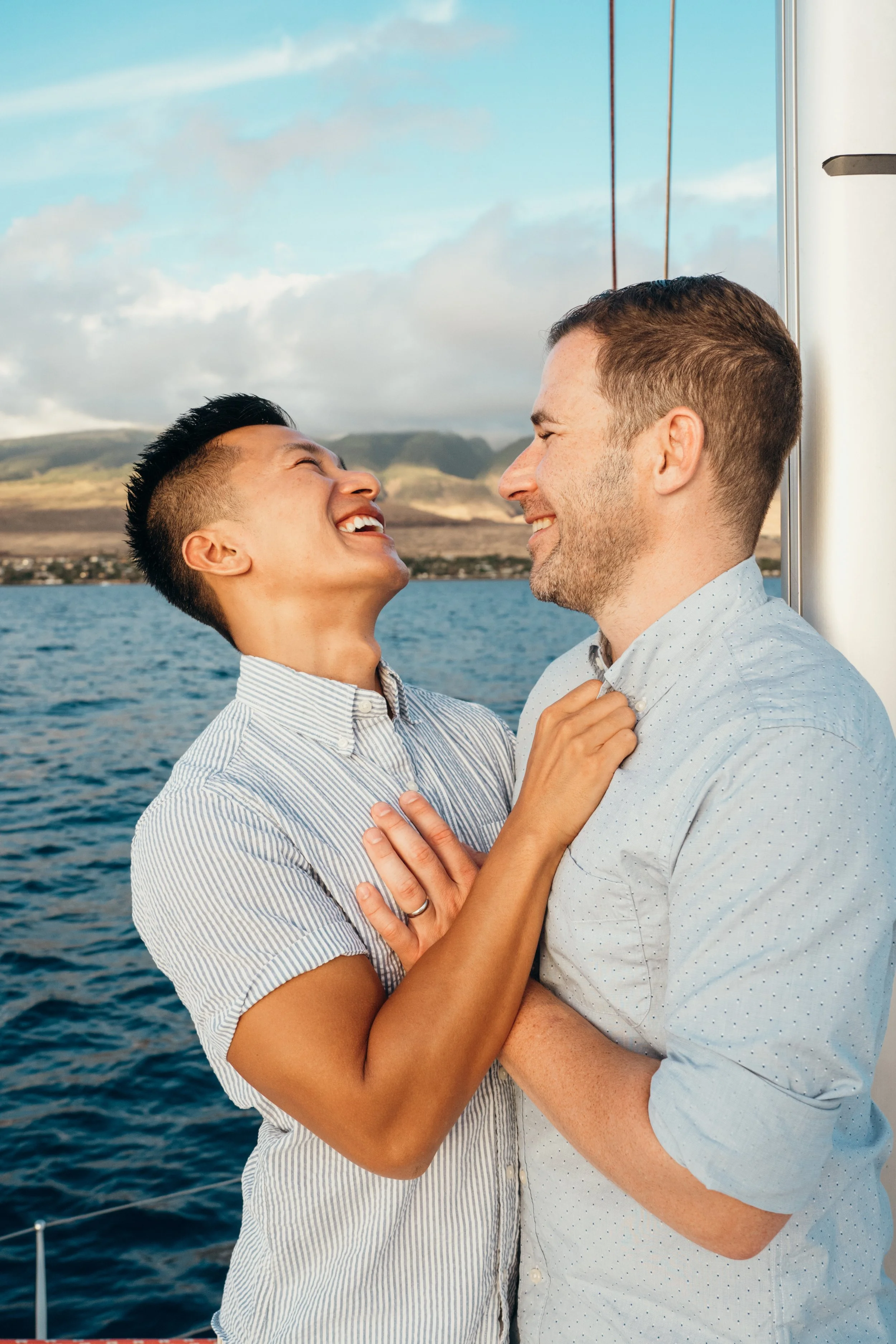 This queer engagement session captures a same-sex couple celebrating on a sailboat. The ocean setting creates a soft, cinematic backdrop. The photographer is based in Colorado and specializes in gay and lesbian elopement storytelling. The style refle