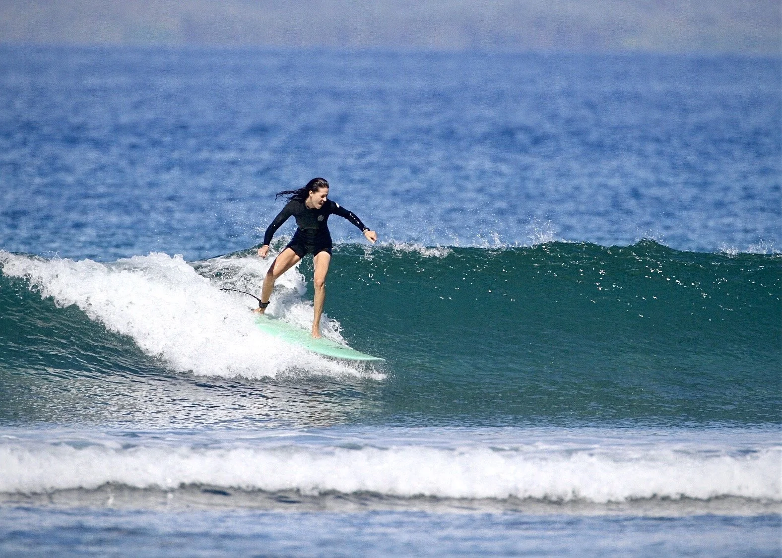 Rachael surfing in Hawaii during an early morning session. Her passion for outdoor adventure helps create relaxed and memorable experiences for photography clients.