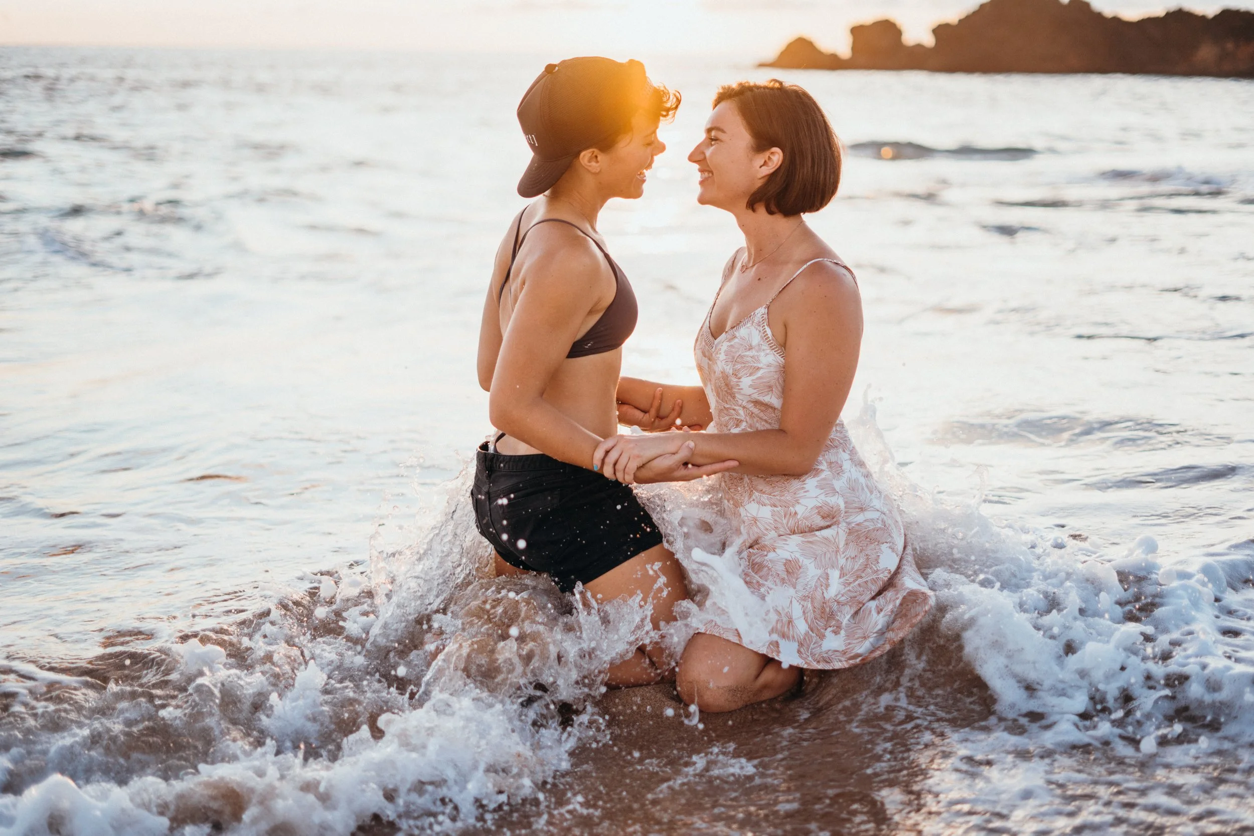 A gay same-sex couple engages in a surf-style session with candid ocean interaction. The movement of the waves creates a dynamic LGBTQ+ storytelling environment. This Colorado-based photographer focuses on queer elopements across Denver, Evergreen, a
