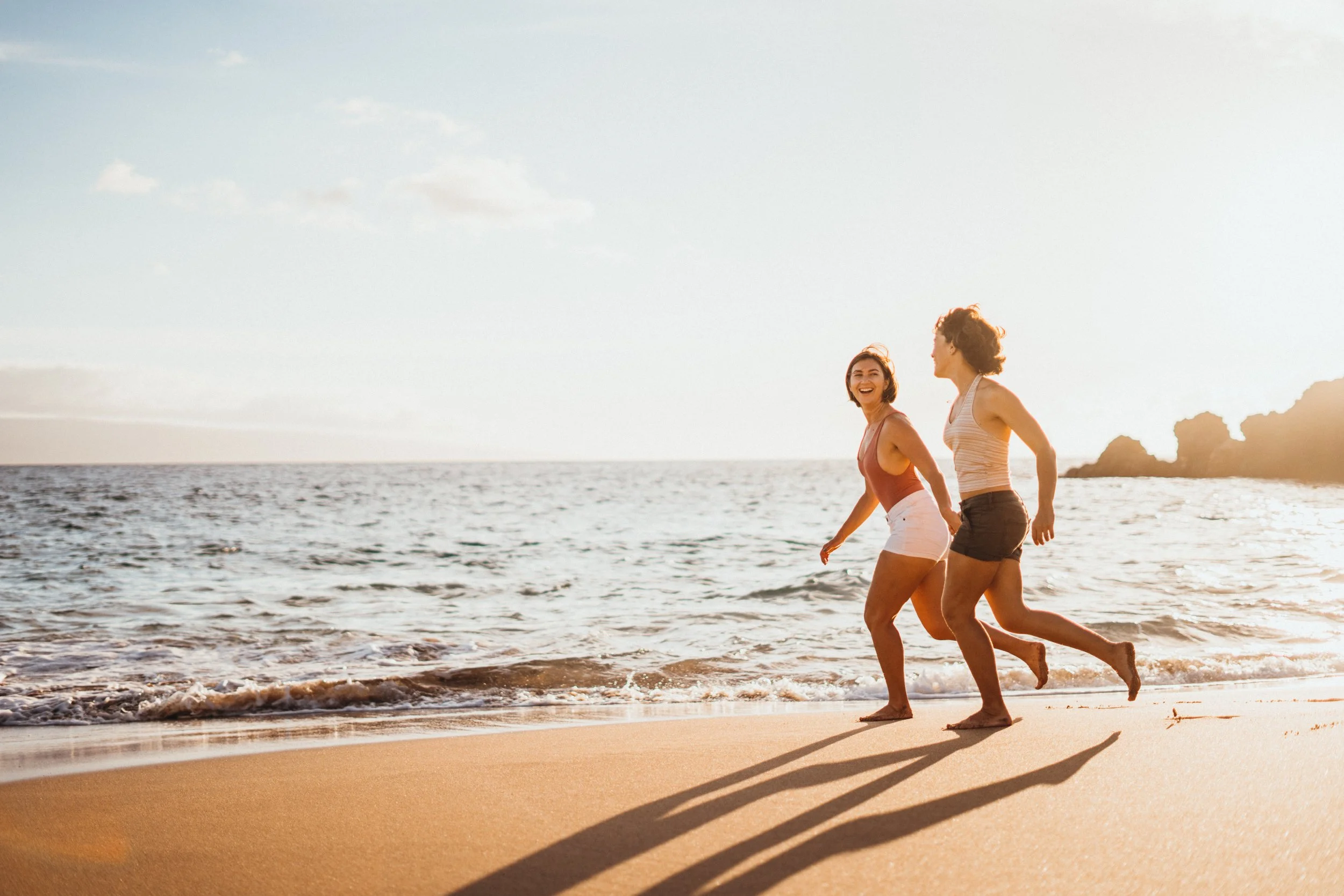 This queer lesbian couple session captures two women in ocean surf during an LGBTQ+ engagement-style shoot. The water creates a playful and emotional environment filled with movement. The photographer is based in Colorado and specializes in gay, lesb