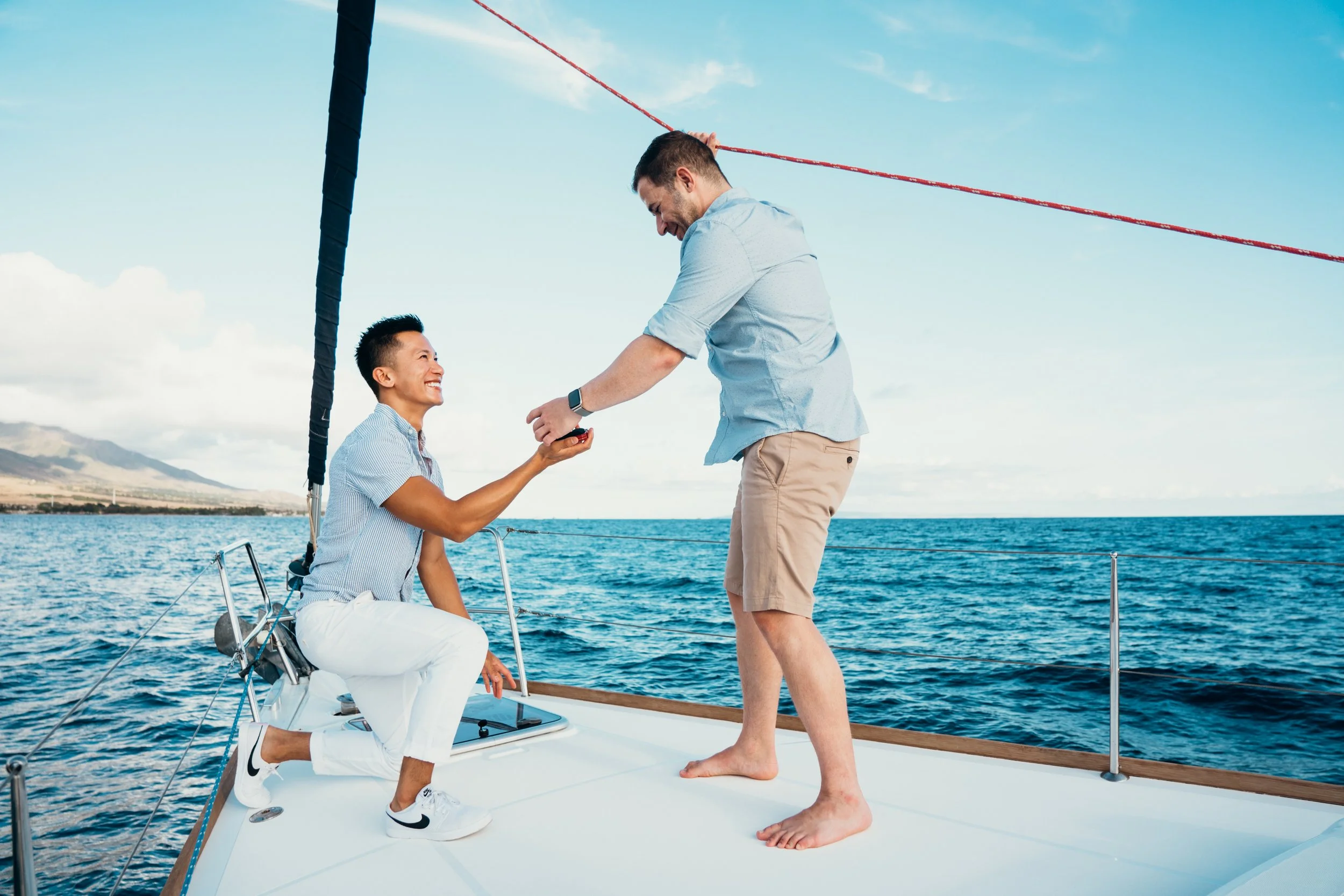 This gay same-sex engagement proposal takes place on a sailboat surrounded by open water and soft light. The couple shares a deeply emotional LGBTQ+ moment in a cinematic ocean setting. The photographer is a Colorado-based queer elopement specialist 