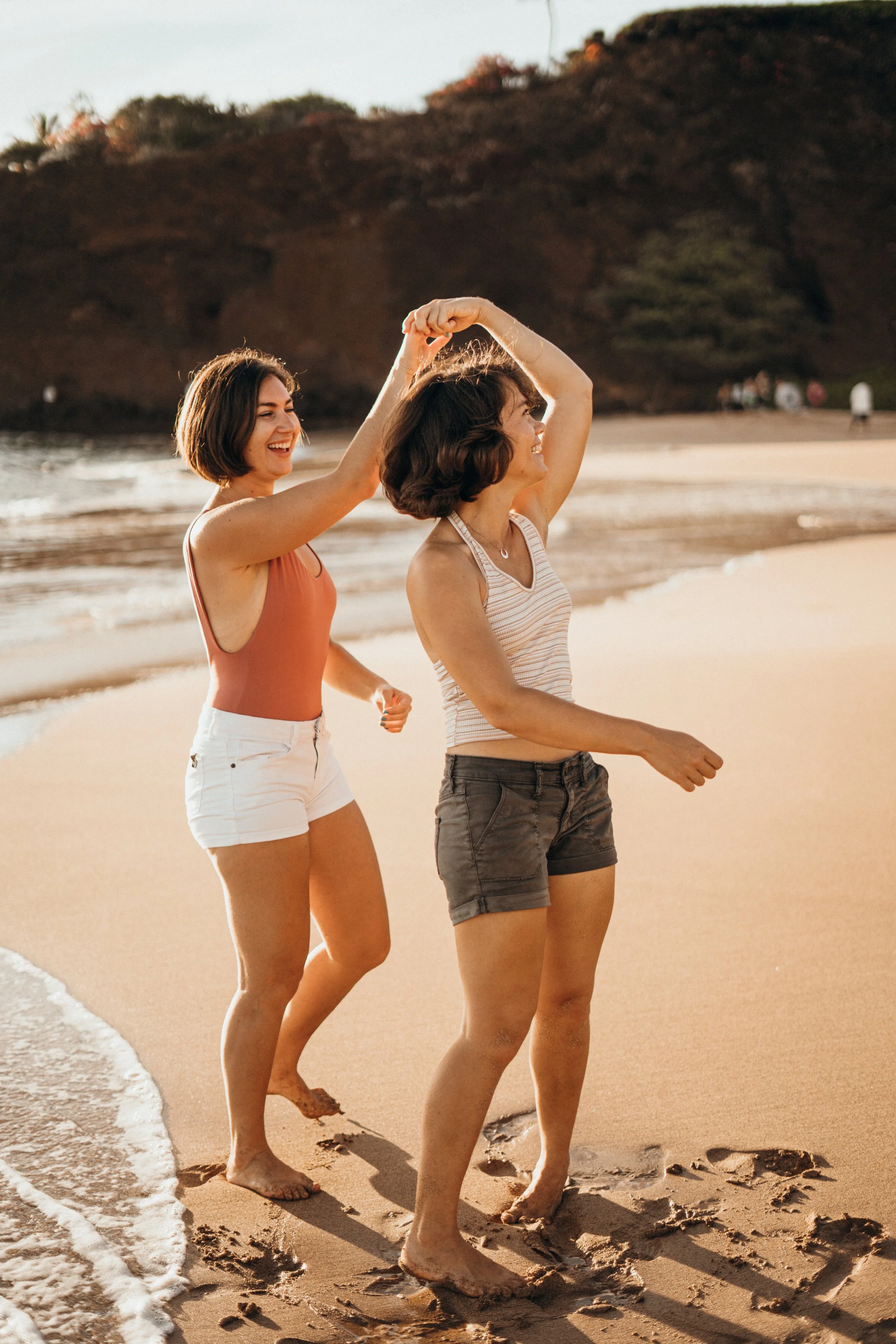 This lesbian surf engagement session captures queer love in a natural ocean environment. The couple is shown interacting freely in the water. The photographer specializes in LGBTQ+ elopements rooted in Colorado storytelling across Evergreen and Bould