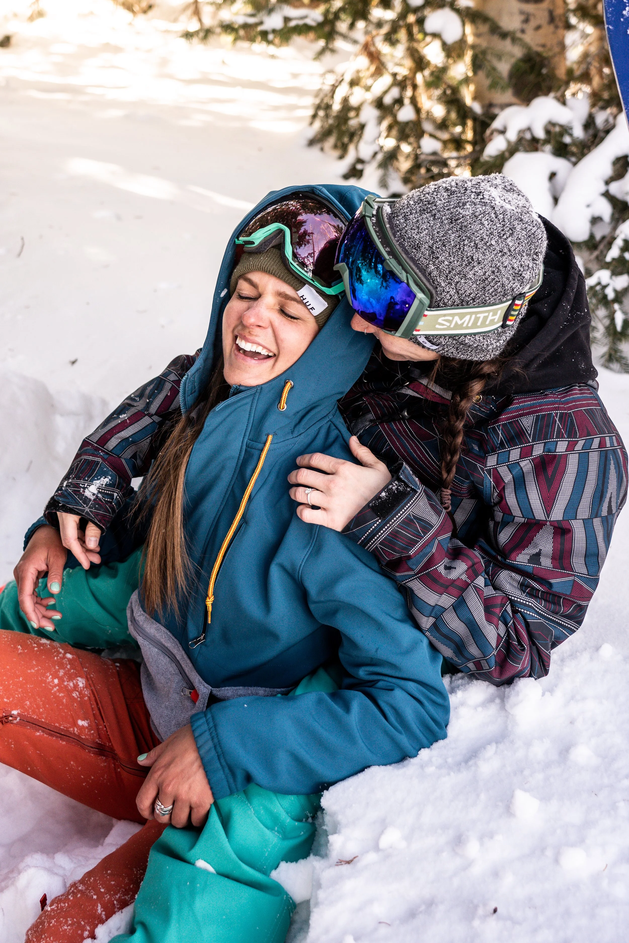 A romantic winter proposal unfolds on a Colorado mountain slope after a snowboard descent. The couple is captured in a genuine emotional reaction surrounded by snow and open sky. This image reflects a Colorado-focused photographer working across Rock