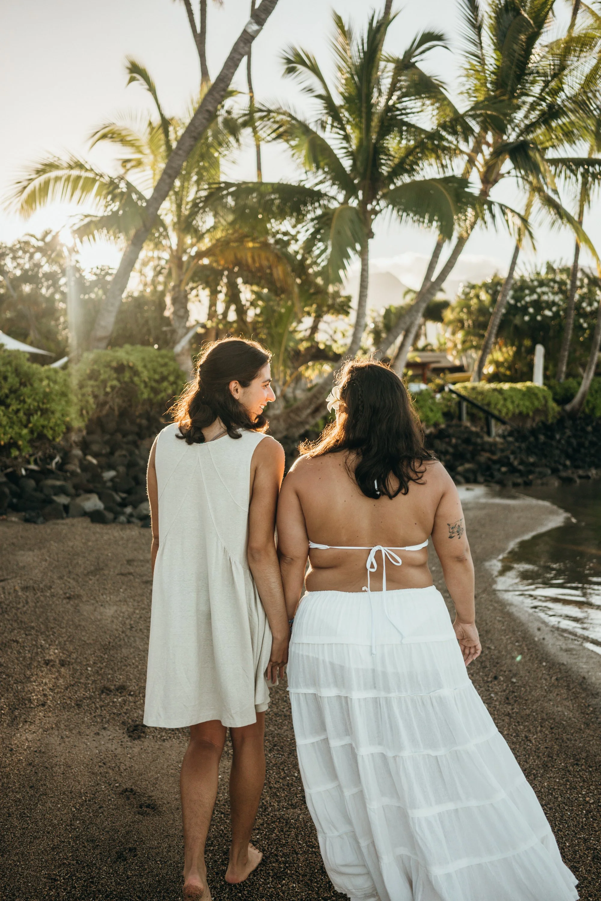 This engagement session shows a same-sex couple celebrating on a shoreline. The waves roll in behind them, creating movement and atmosphere. The moment is captured in a candid documentary style. Even though this image was taken in Hawaii, it fits wit