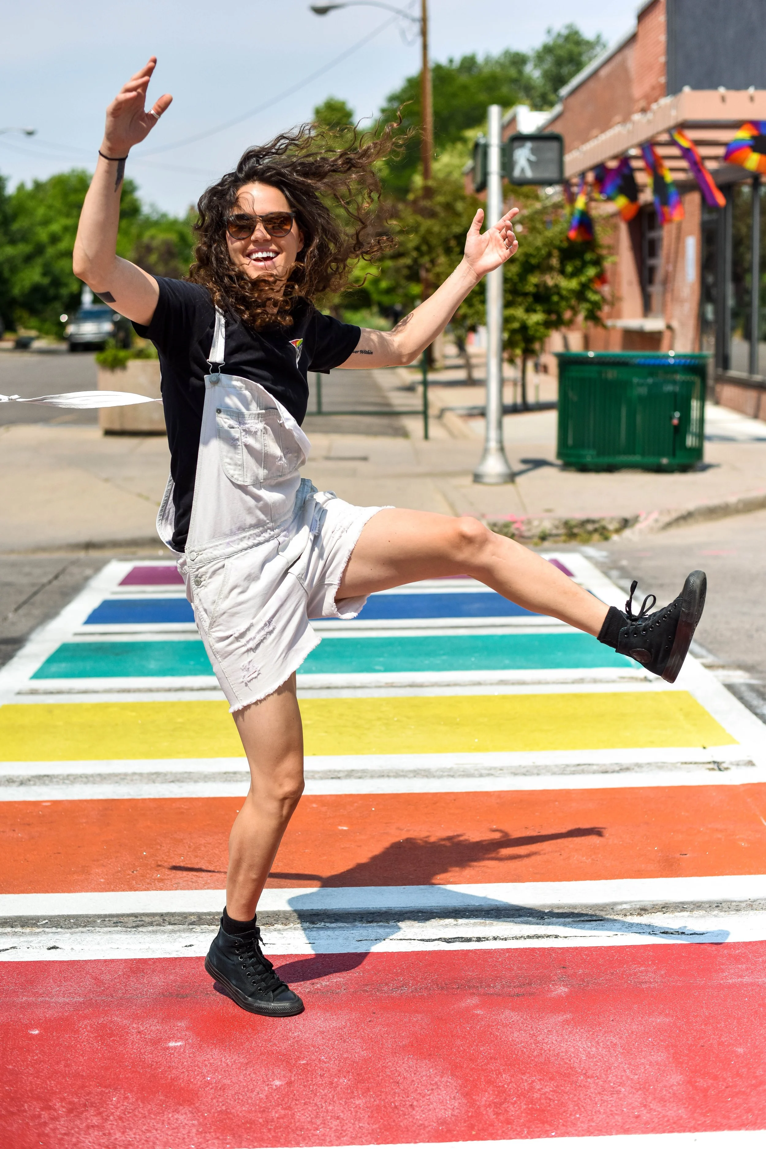 LGBTQ+ Colorado Photographer walking across rainbow crosswalk in Denver