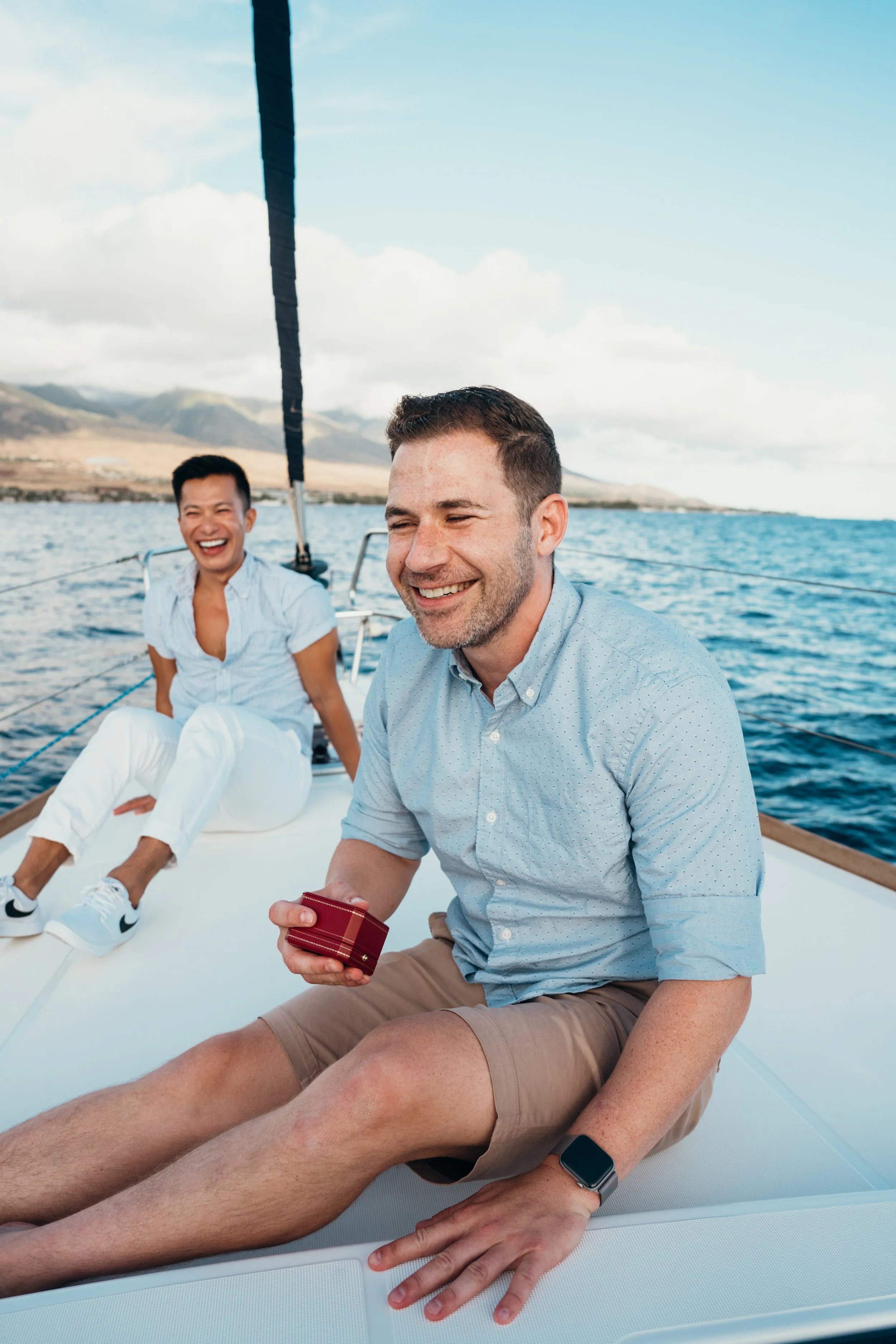A gay engagement proposal is documented on a sailboat surrounded by ocean and sky. The couple shares a quiet queer moment of connection after the proposal. This Colorado-based LGBTQ+ photographer specializes in adventure elopements across mountain an