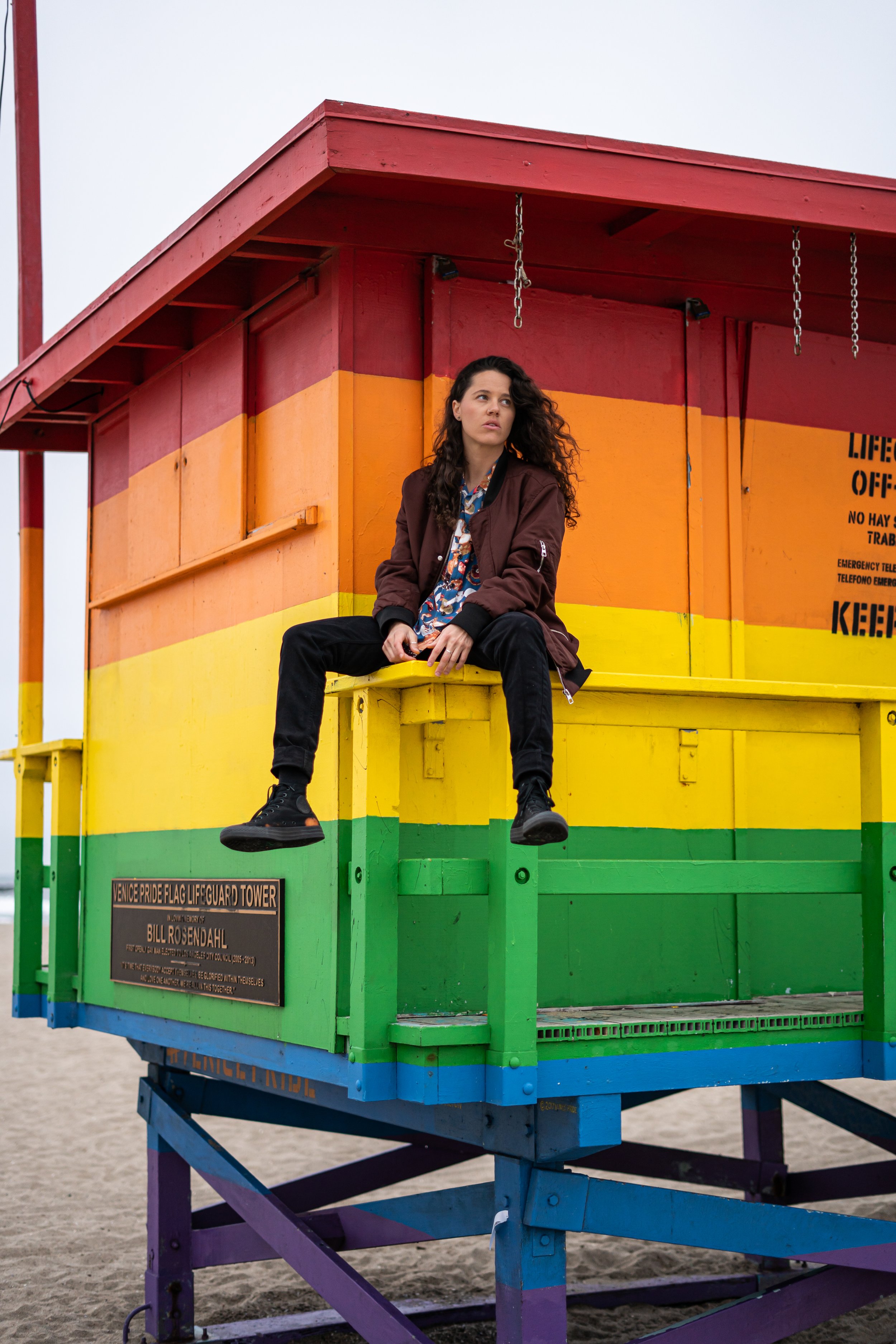 Rachael standing in front of a rainbow art installation while documenting LGBTQ+ community spaces. Representation and visibility have remained central themes throughout her photography career.