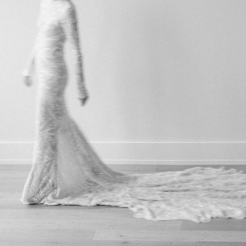 A woman in a long, elegant dress walking on the floor.