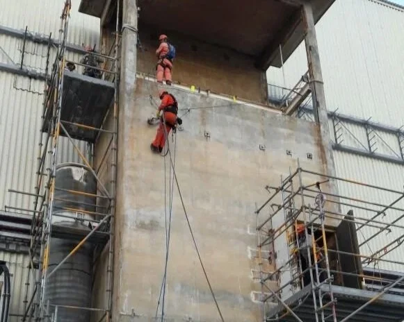Trabajadores en una construcción, colgados en una cuerda, en una estructura de edificio en proceso