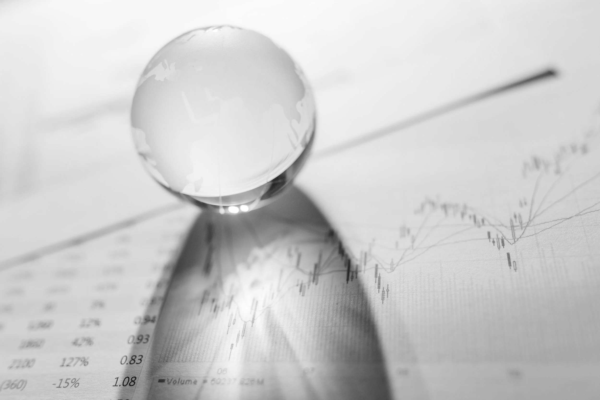A glass globe placed on a sheet of paper displaying financial graphs and stock market data.