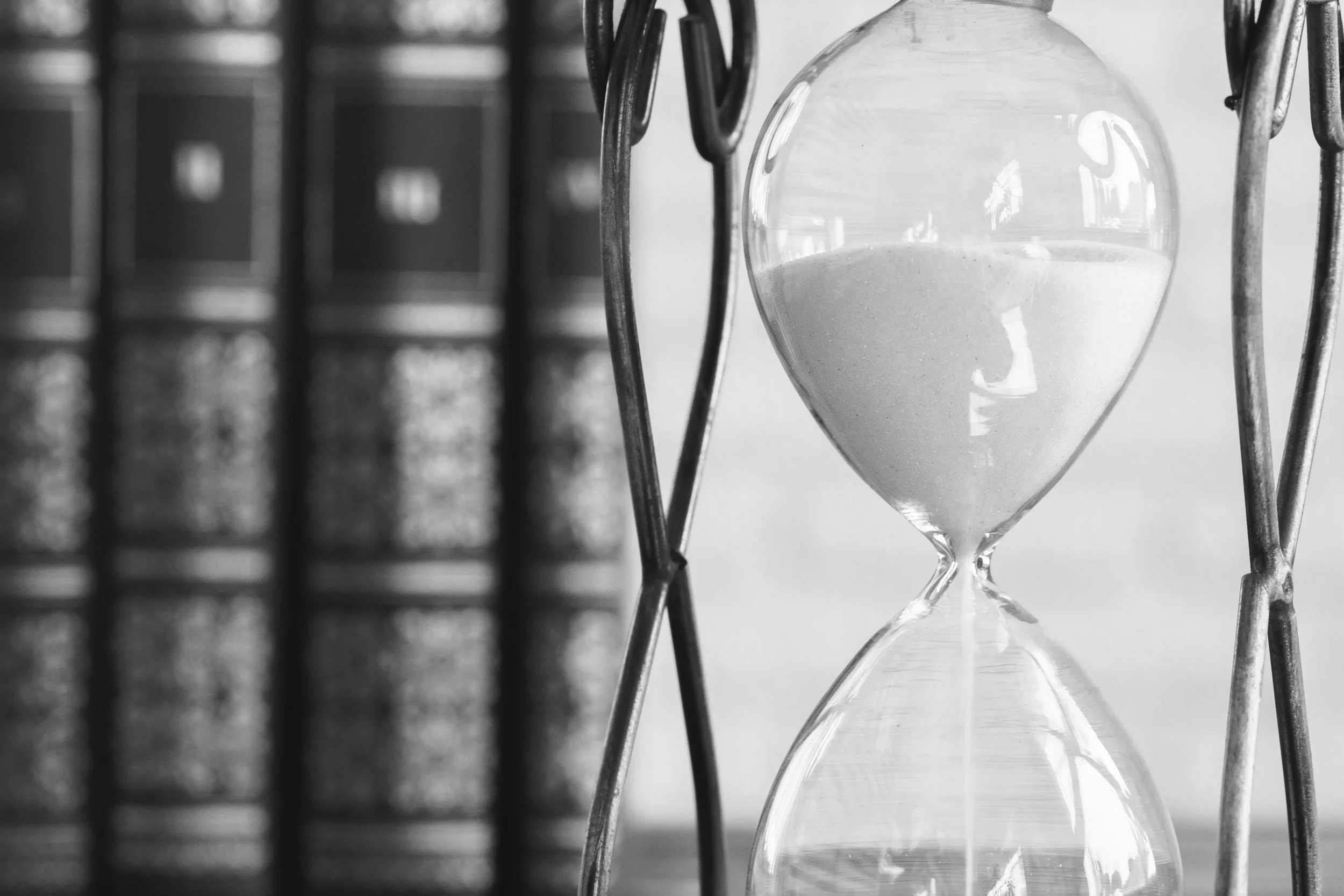 A black and white photo of an hourglass with sand.