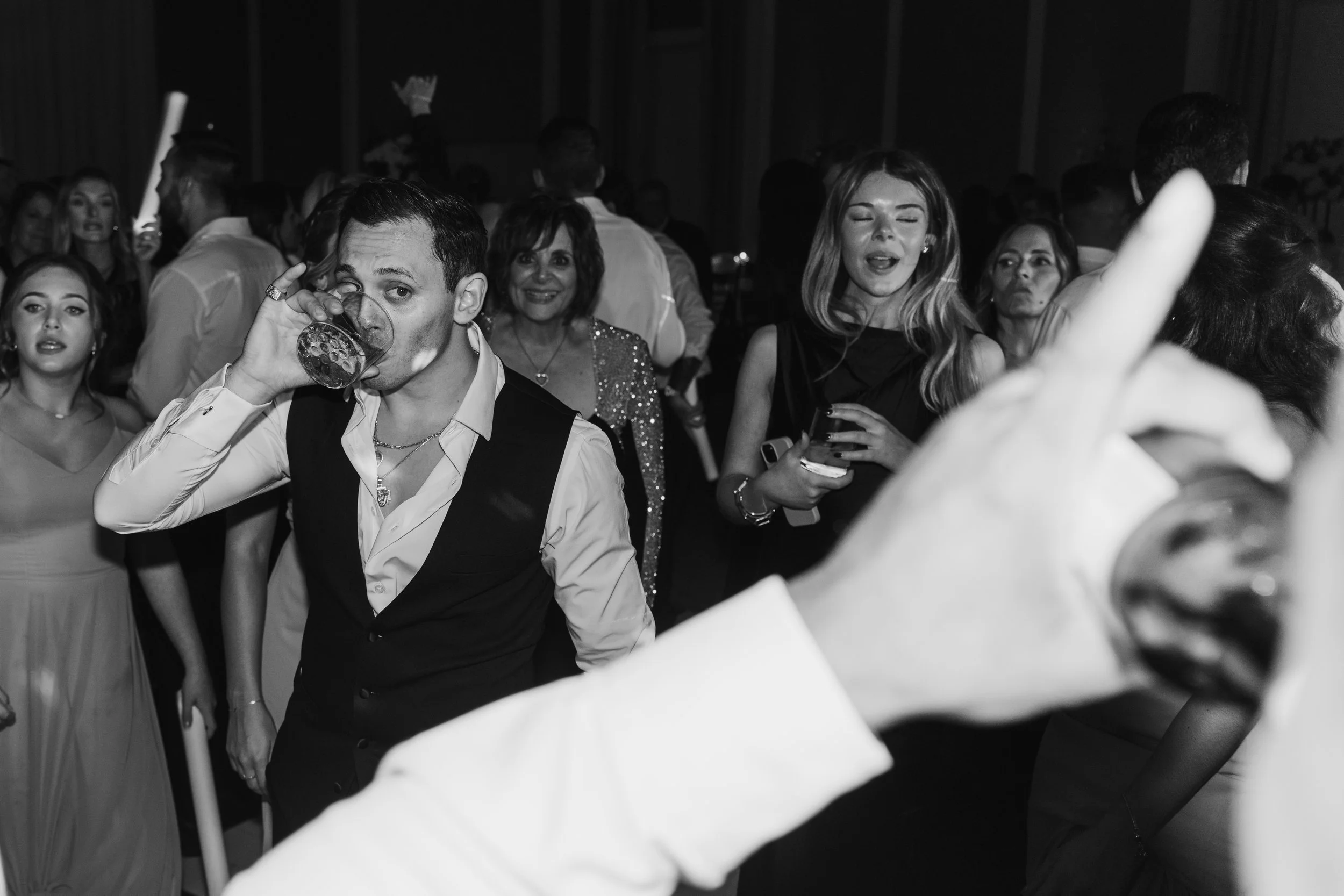 People dancing and socializing at a party or celebration, with some holding drinks and others chatting.