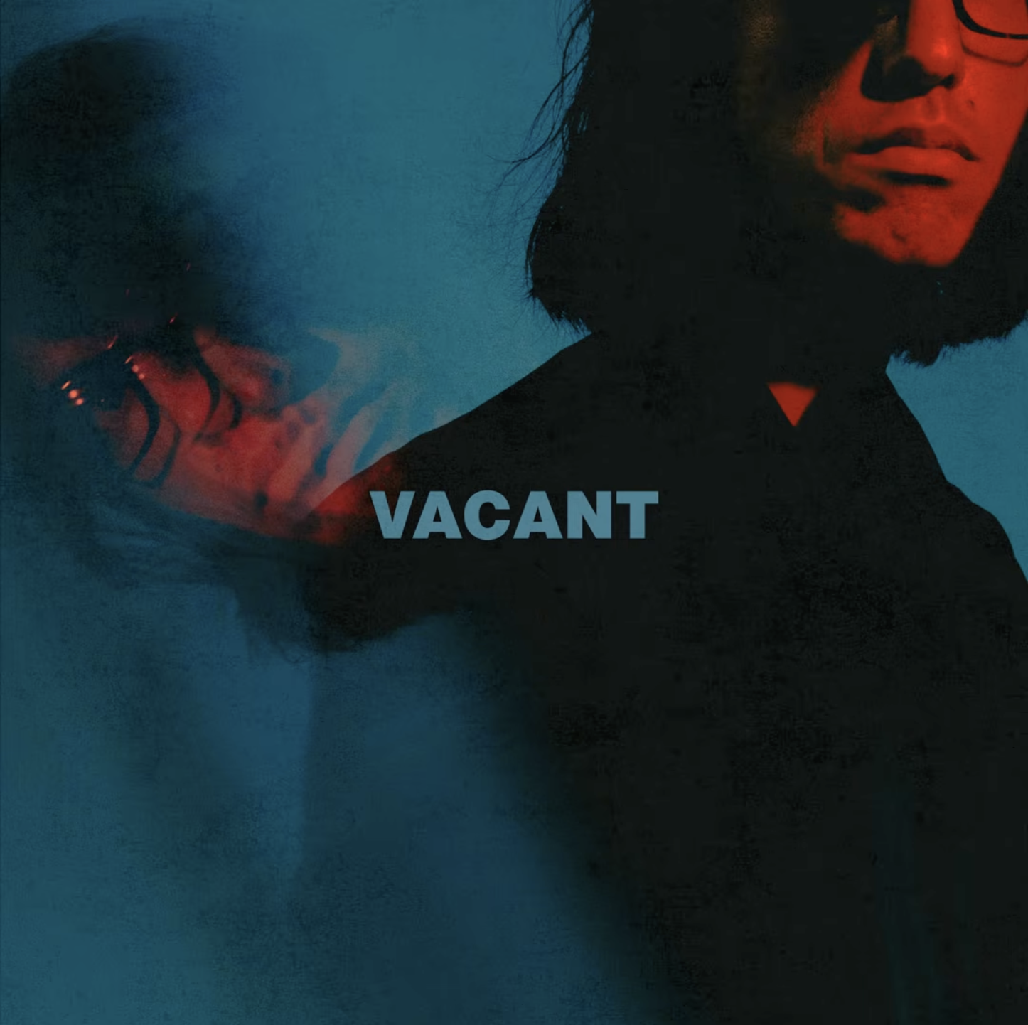 A woman with short dark hair and glasses, looking to the right, with the word 'VACANT' in blue text in the center.