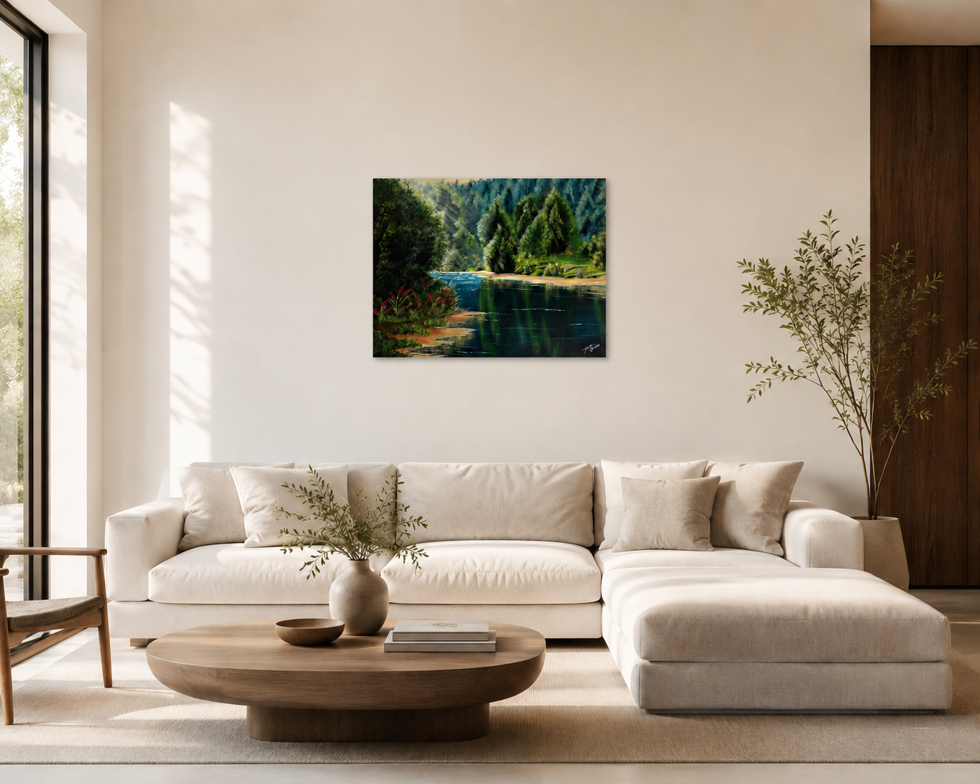 Living room with a cream sectional sofa, a round wooden coffee table with a vase and books, large window with natural light, landscape painting of a river and trees on the wall, and potted plants for decor.