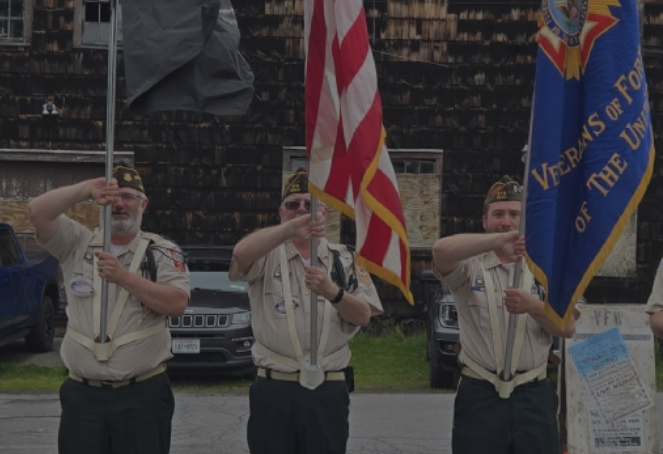 Three veterans in uniform holding flags, saluting during a parade or ceremony.