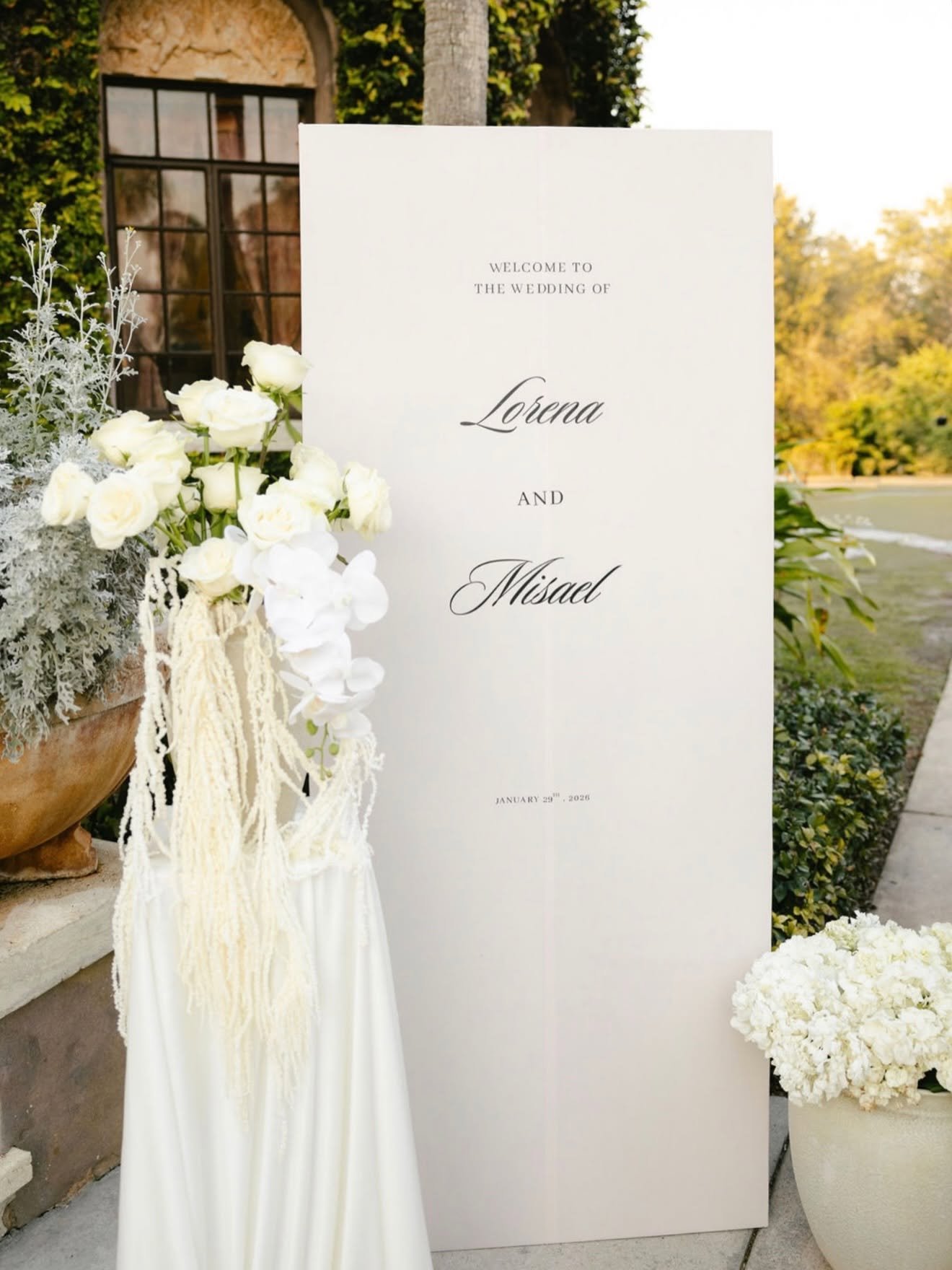Wedding welcome sign with white flowers and greenery outdoors, date January 29, 2023