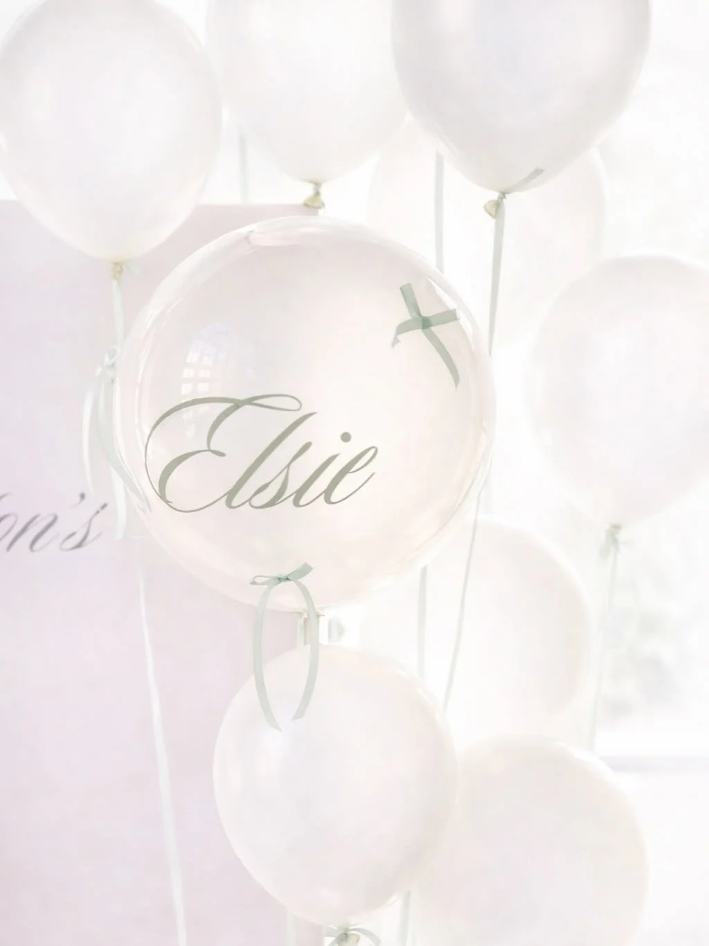 White balloons, one with the name Elsie written on it, close-up, celebrating a special occasion.