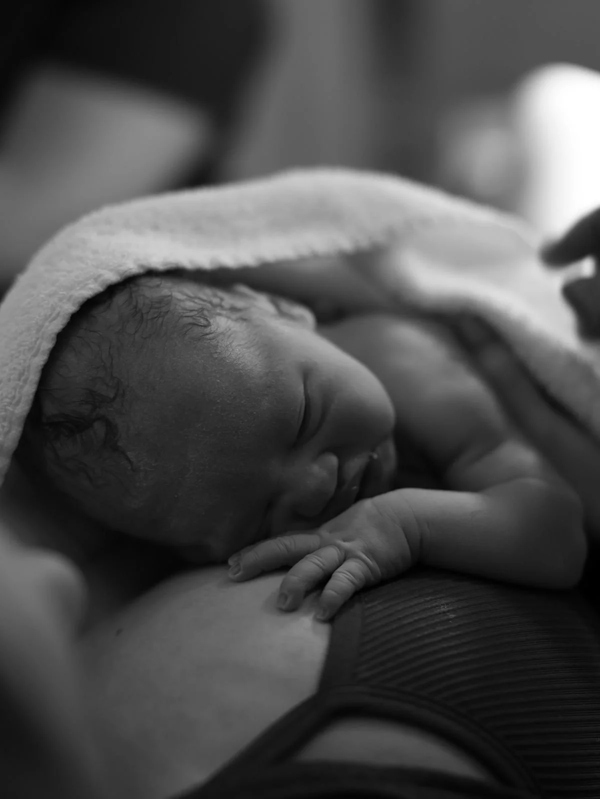 Newborn sleeping peacefully in a loved one’s arms during a quiet moment of postpartum care.