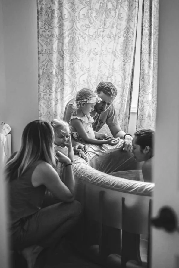 Family gathered together during an intimate home birth, surrounded by love and support.