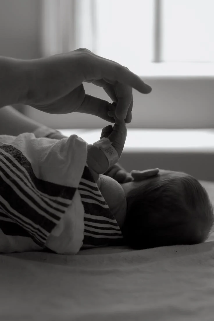 Mother holding her newborn's hand during an in-home postpartum visit.