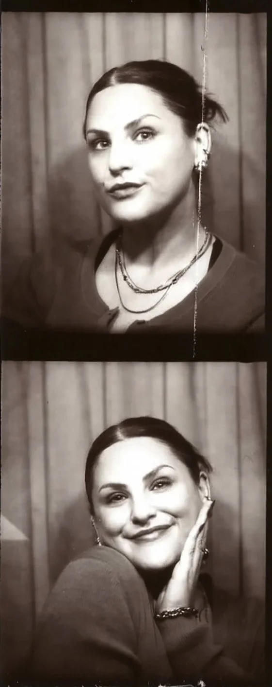 Black and white photo of a woman with dark hair tied back, wearing a cardigan and layered necklaces, making different facial expressions in two different shots with a curtain background.