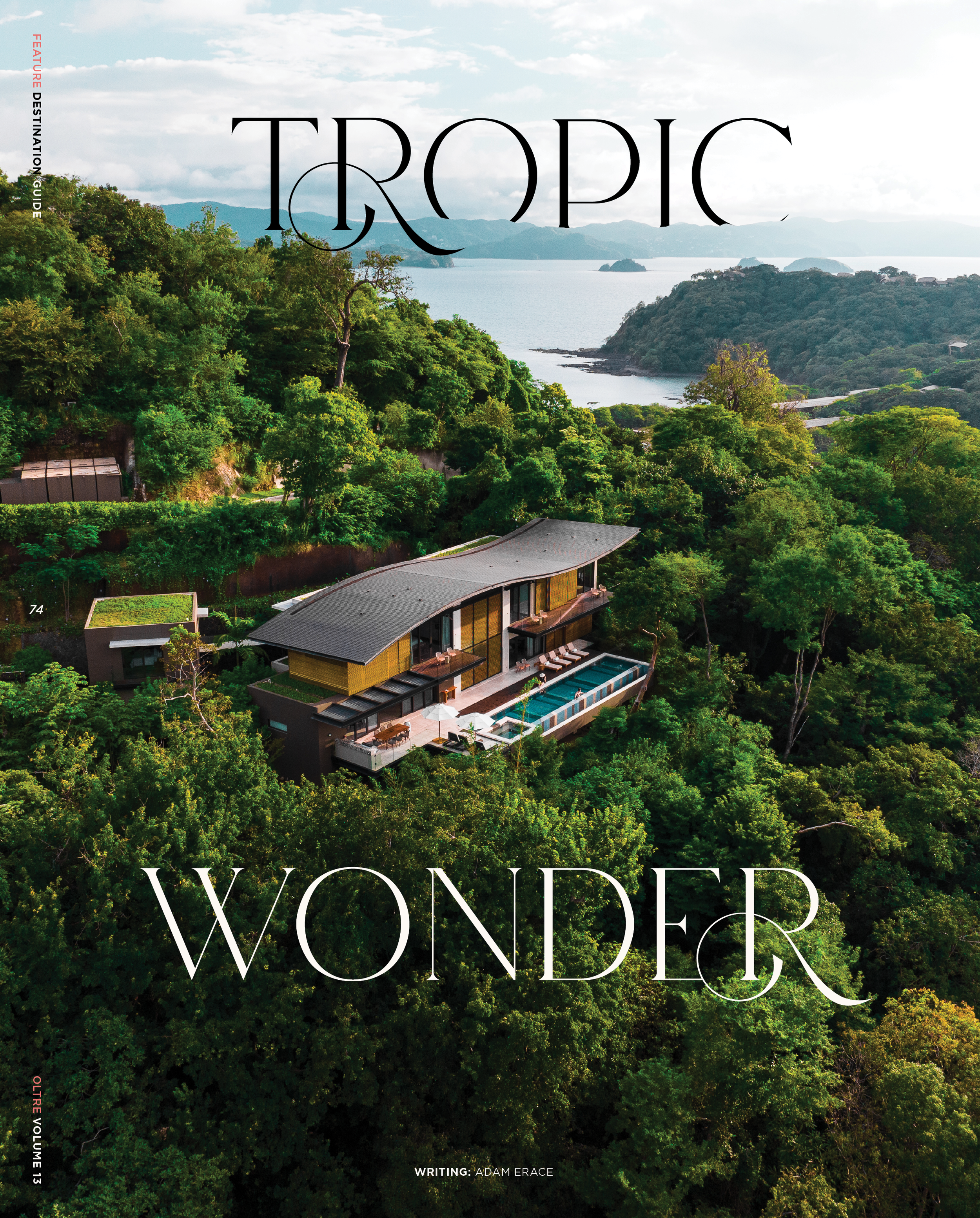 A lush green tropical forest with a modern building and a swimming pool in the foreground, overlooking a body of water and distant mountains under a cloudy sky.