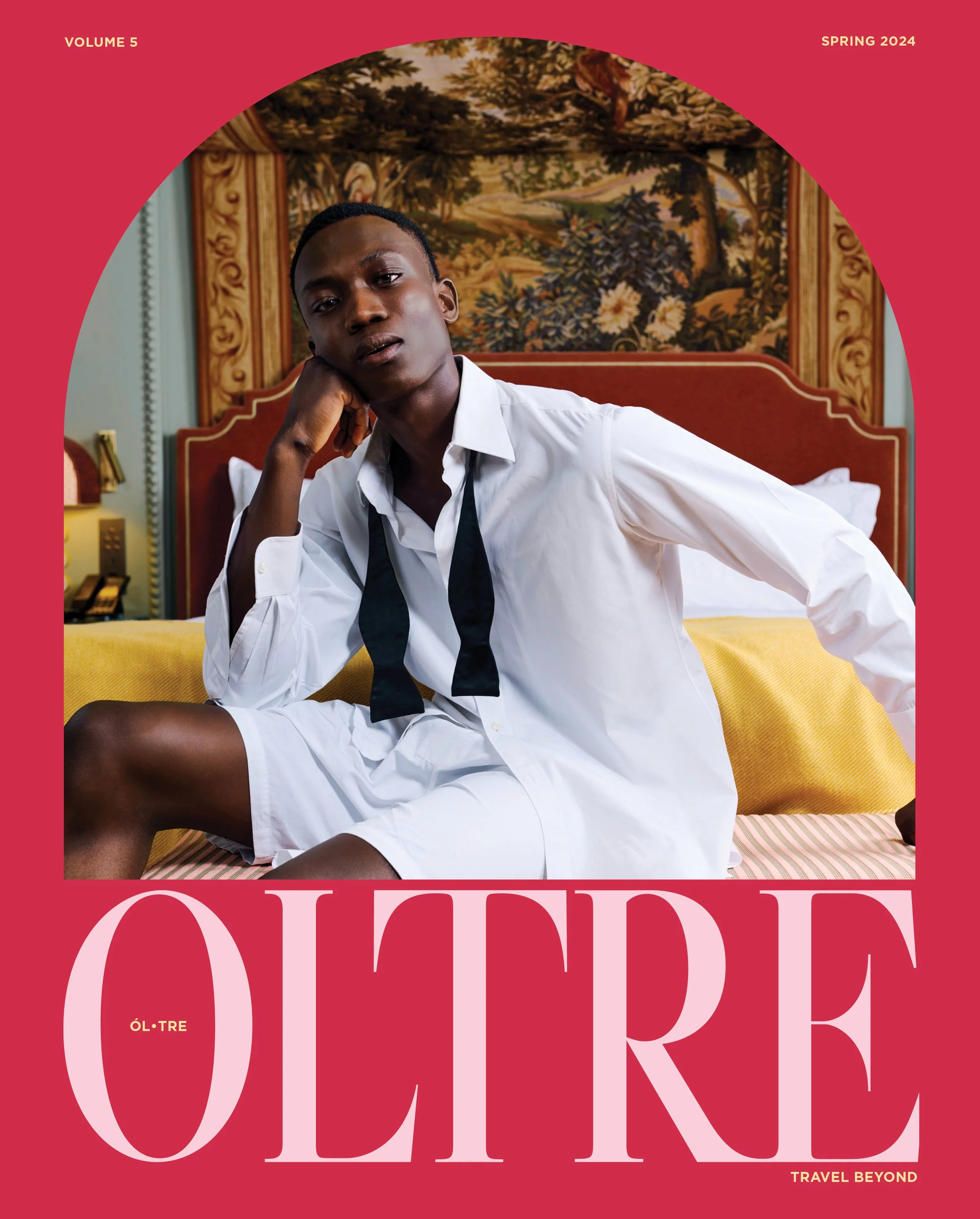 Cover of a magazine featuring a young man sitting on a bed with a decorative tapestry behind him, wearing a white shirt and black tie, with the magazine title partly visible in large pink letters.