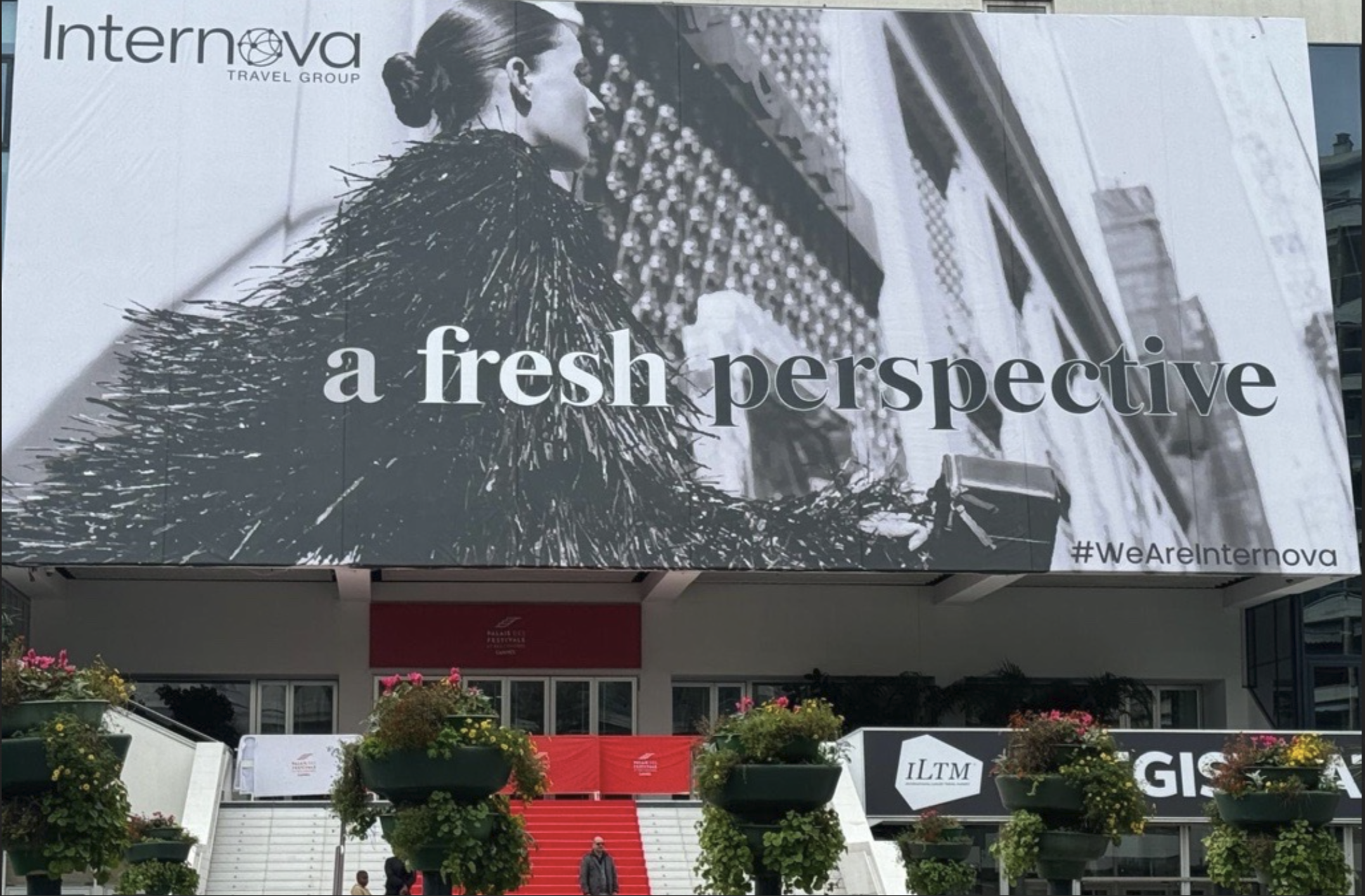 A large billboard with a black-and-white image of a woman with her hair in a bun, looking to the side, over a textured background. The billboard includes the words "a fresh perspective" and the hashtag #WeAreInternnova. Below the billboard is a set o