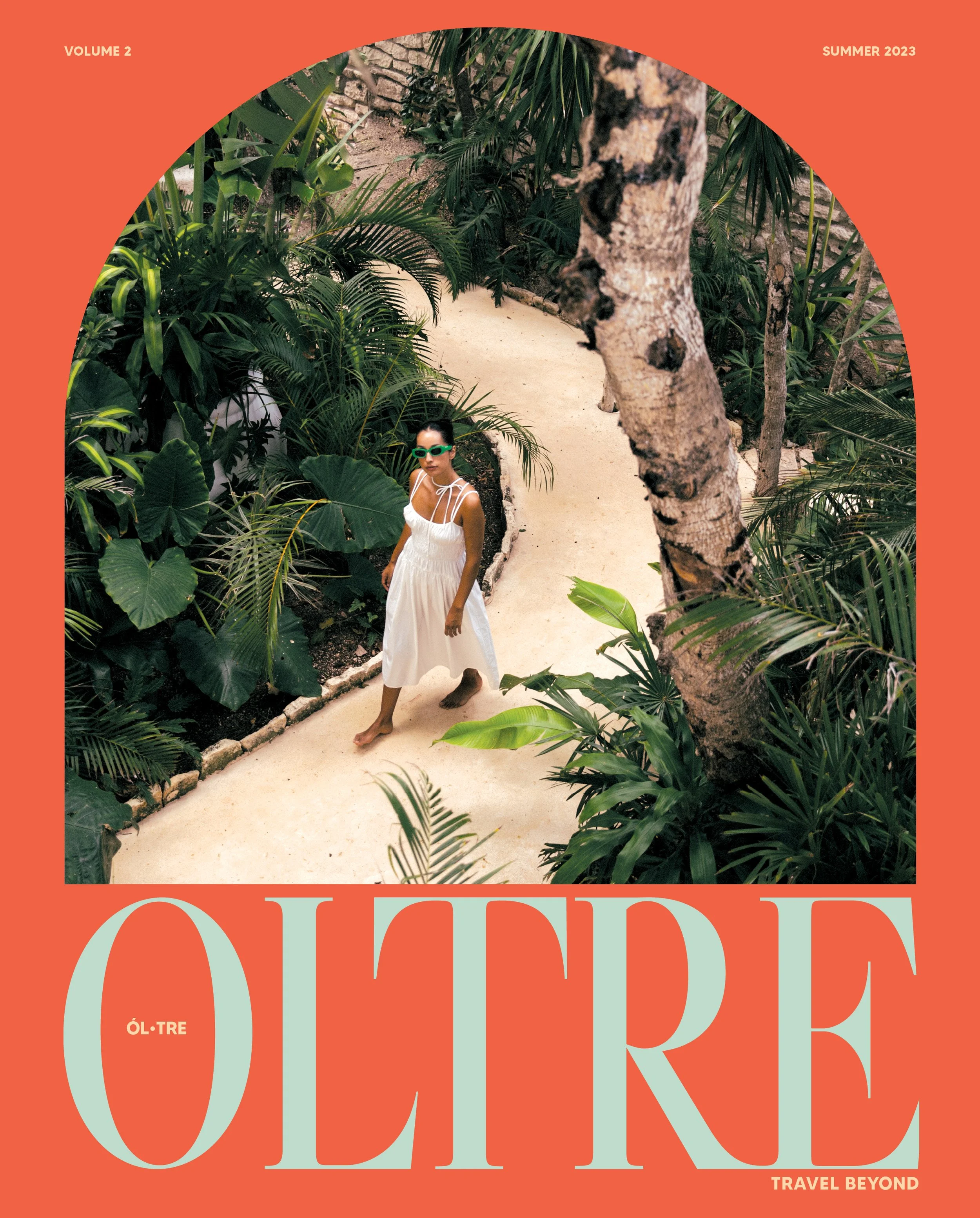 Cover of a magazine or book titled 'ÓL-TRE' with a tropical scene featuring a woman in a white dress and green sunglasses, walking along a path surrounded by dense green plants and trees. The top border has text indicating 'VOLUME 2', 'SUMMER 2023', 