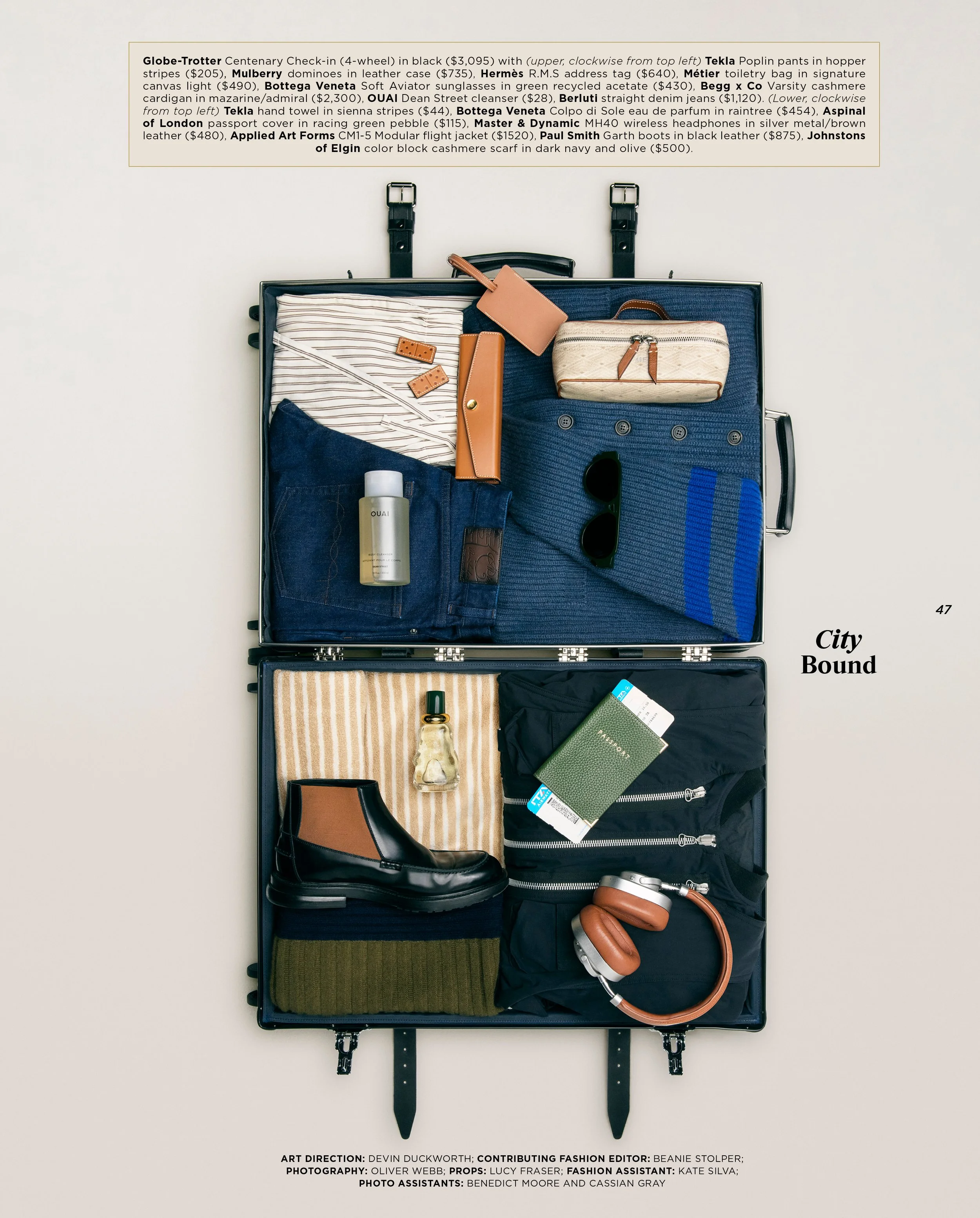 Open black suitcase containing clothing and accessories. Items include a striped shirt, denim jeans, a beige and brown striped handbag, a pair of sunglasses, a bottle of perfume, a black bag, a pair of brown headphones, and a green passport holder.