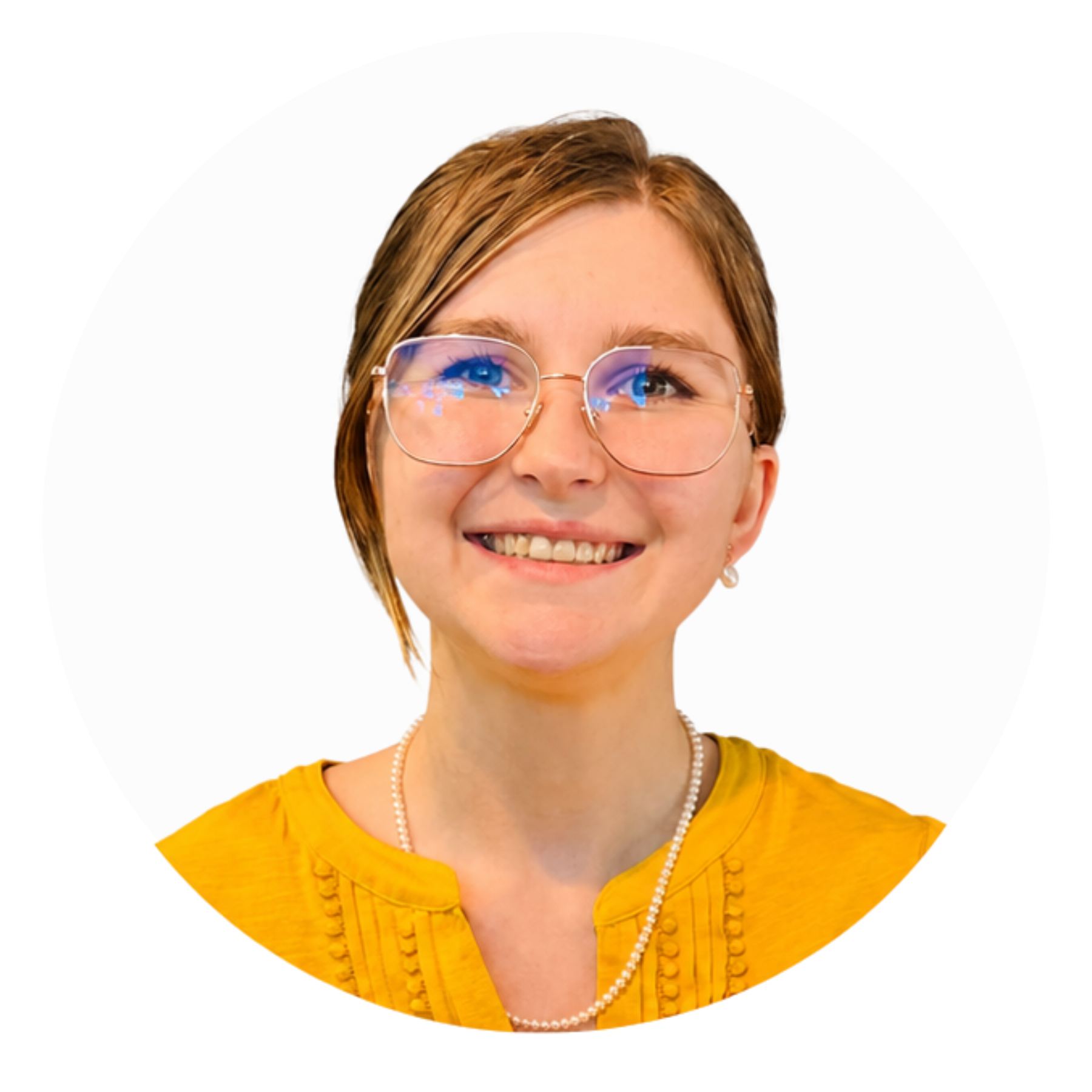 Close-up of a woman with short brown hair, wearing glasses and a yellow top, smiling against a white background.