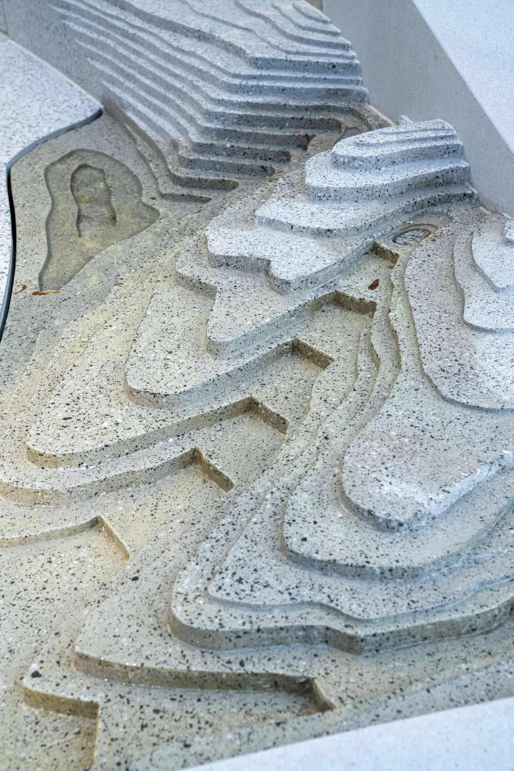Close-up of a textured stone sculpture with layered, wavy patterns and carved-out sections.