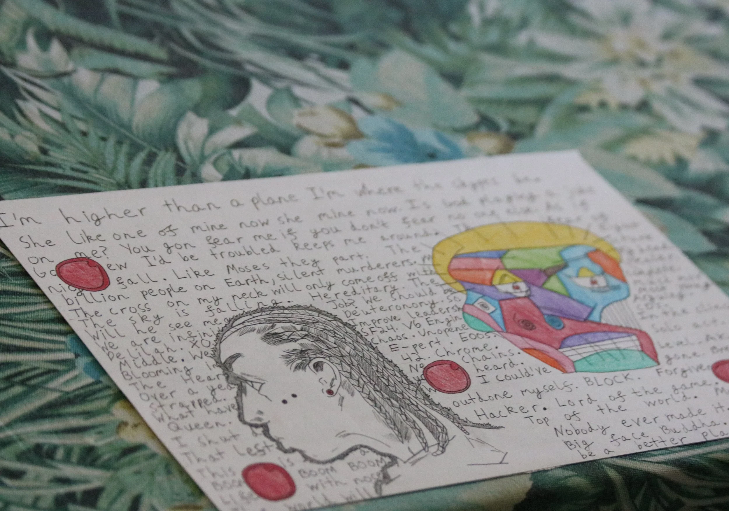 A handwritten letter on paper with colorful rainbow and cloud illustrations, placed on a surface with green leafy pattern.