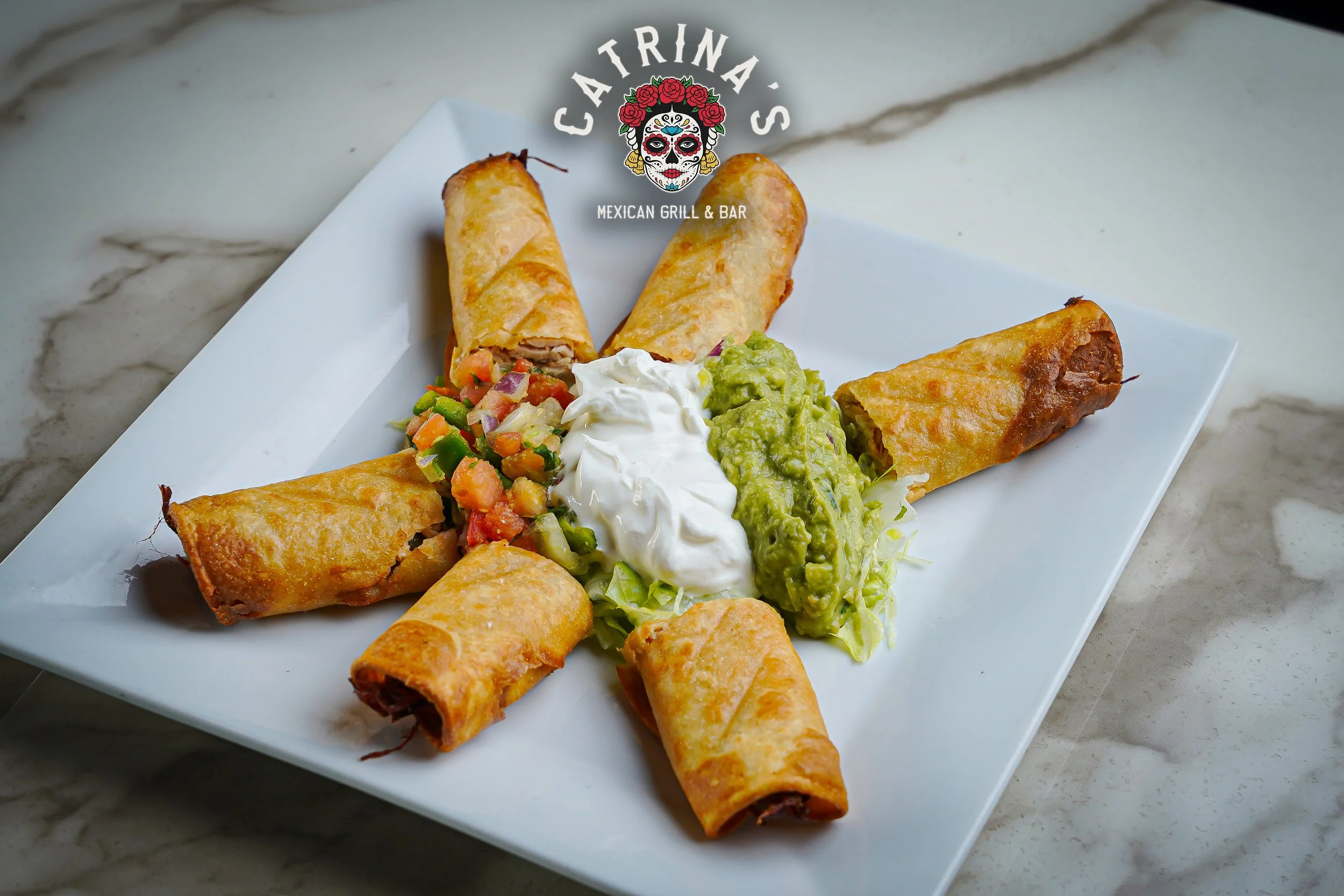 Plate of crispy Mexican spring rolls filled with meat, served with guacamole, sour cream, and pico de gallo on a white rectangular plate.