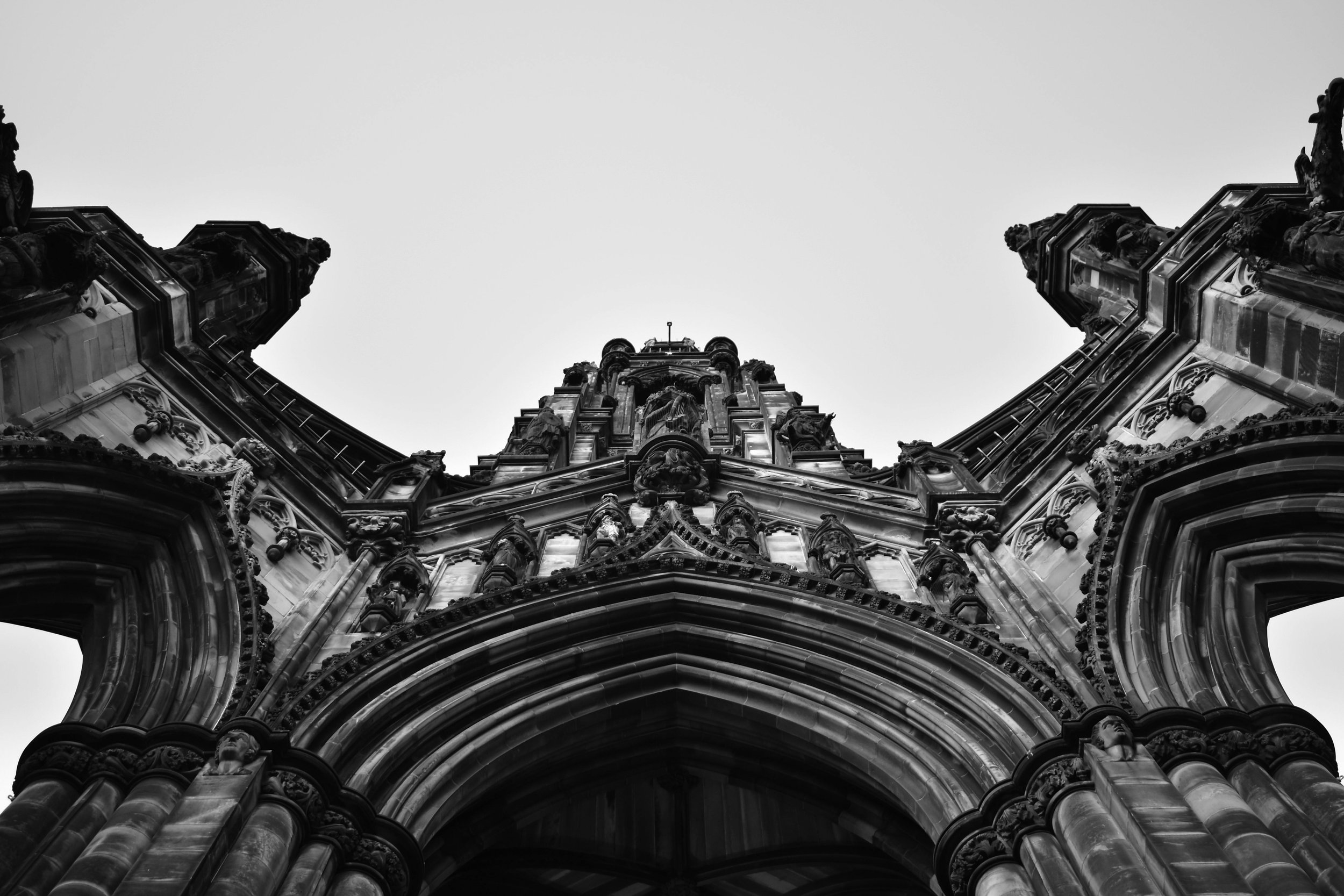 A black and white photograph taken from below captures the ornate Gothic architecture of the Scott Monument in Edinburgh.