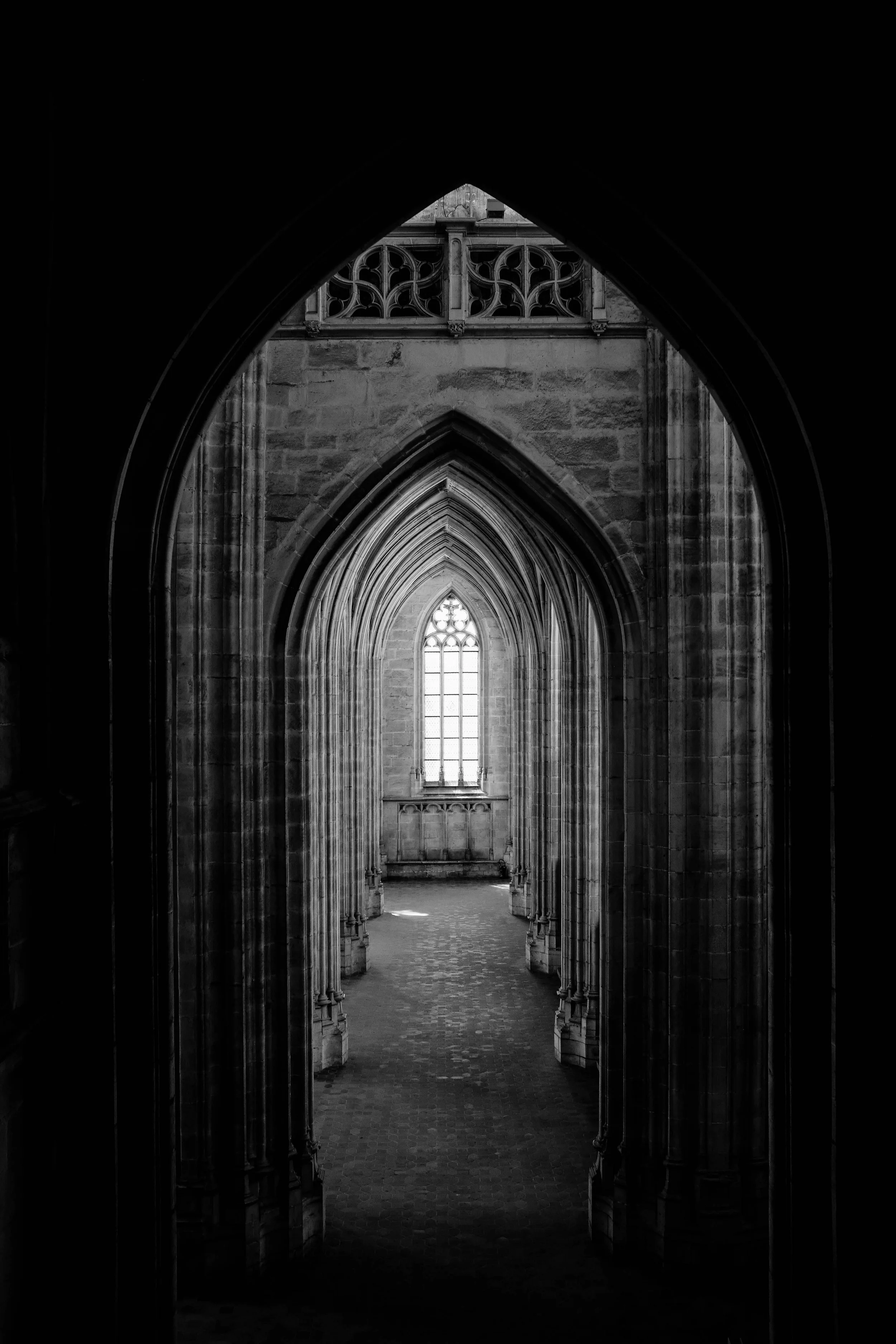 Black and white photo of a Gothic cathedral's arched interior hallway in Glasgow.