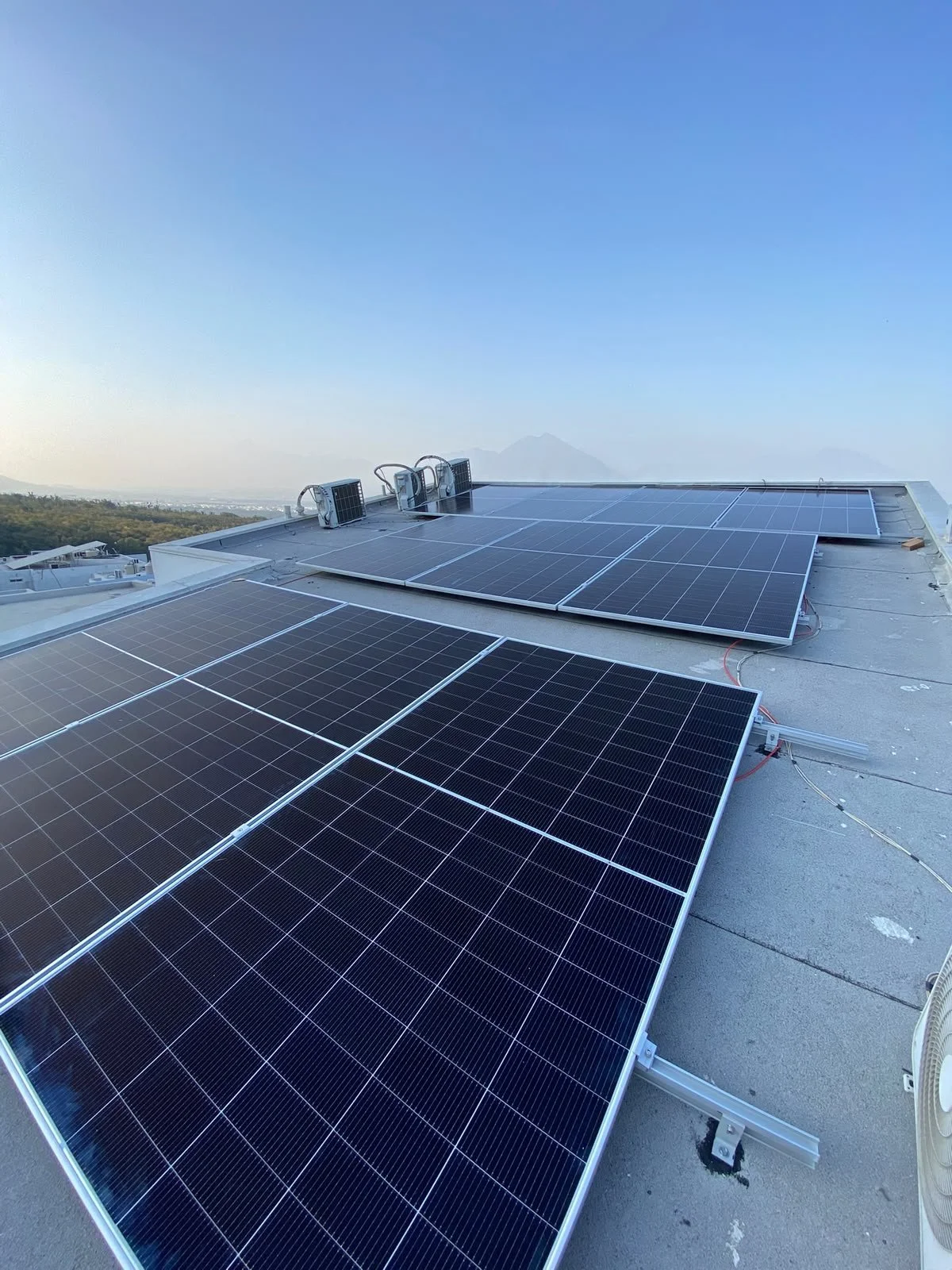 Paneled placas solares instaladas en el techo de un edificio con vista de fondo a un cielo despejado y montañas a lo lejos.