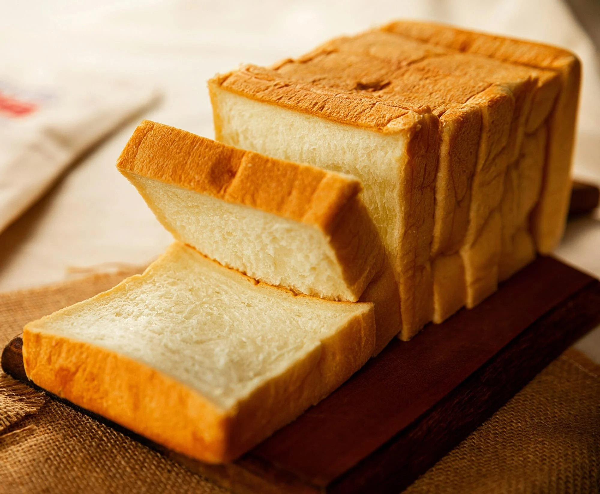 Slices of white bread stacked on a wooden surface.