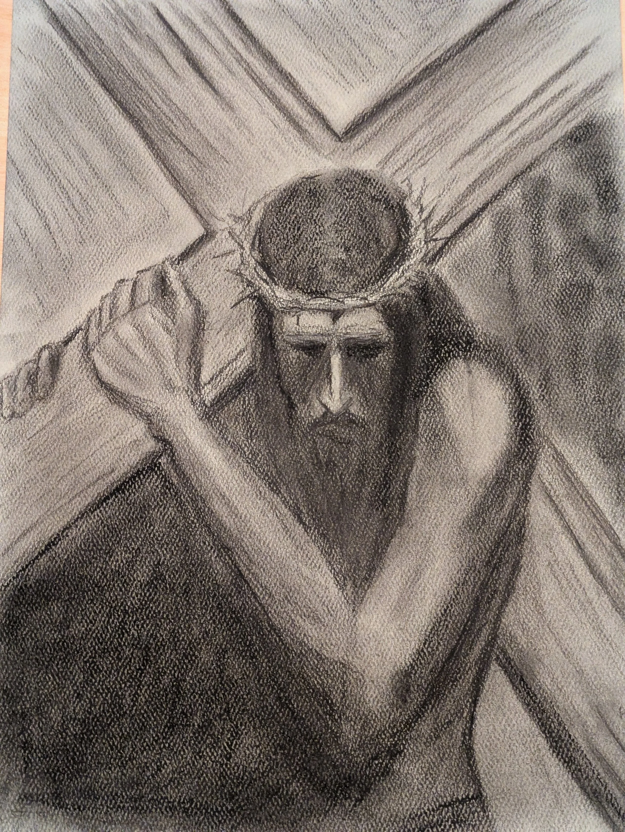 A detailed charcoal drawing of Jesus Christ holding the cross. Dark and gray colors.