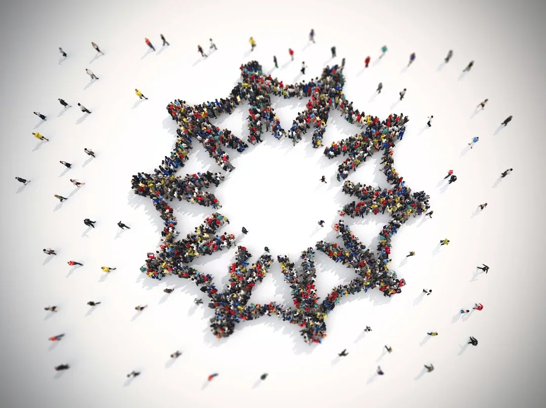 Aerial view of a large crowd of people forming a circle with outstretched arms, like people holding hands.