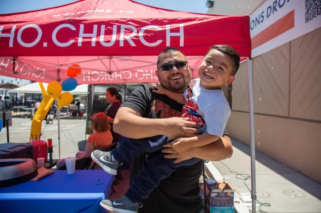 Jose Fontanillo holding his son Jojo at an outdoor community event.