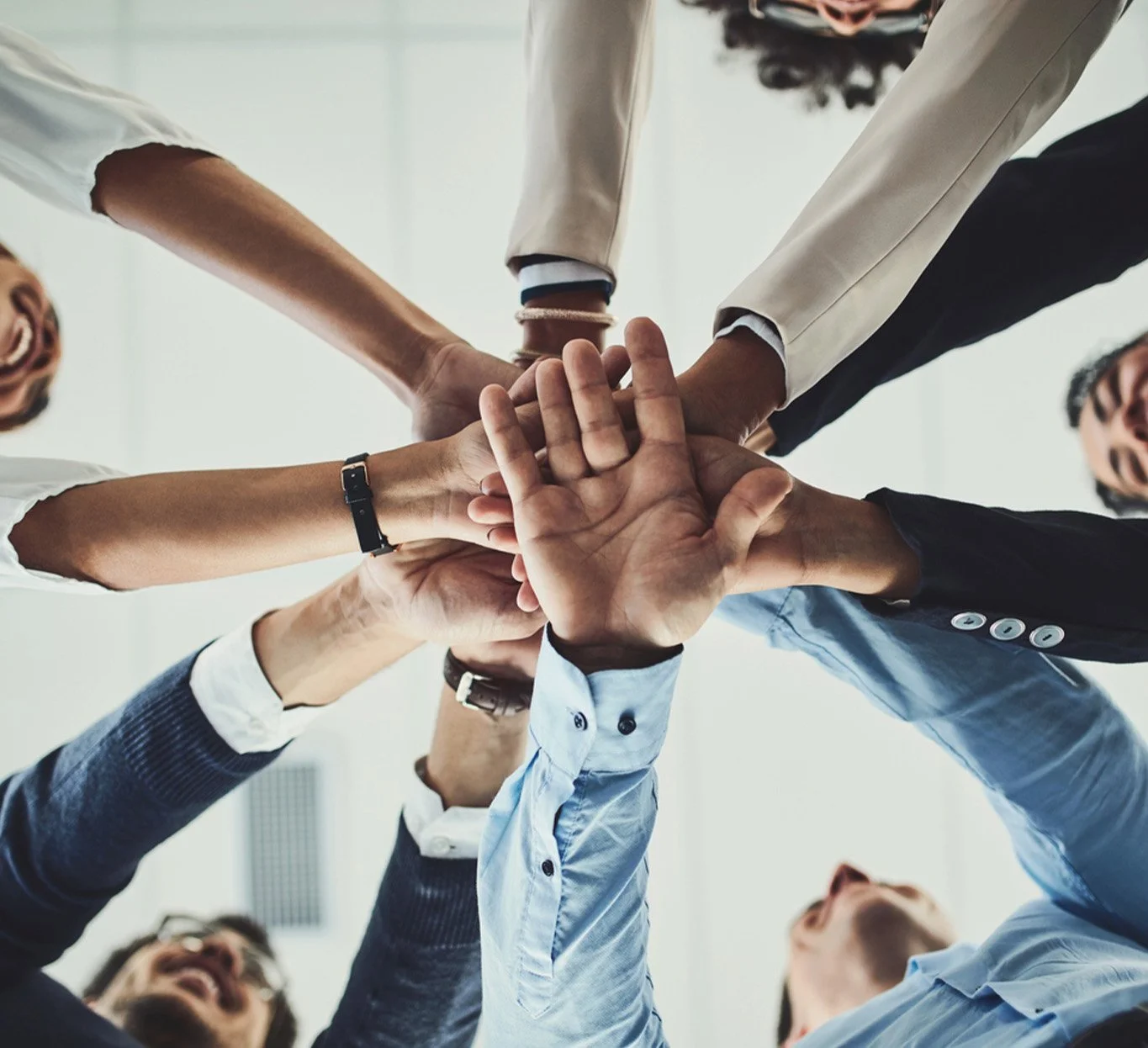 A group of people stacking hands together in a show of teamwork.