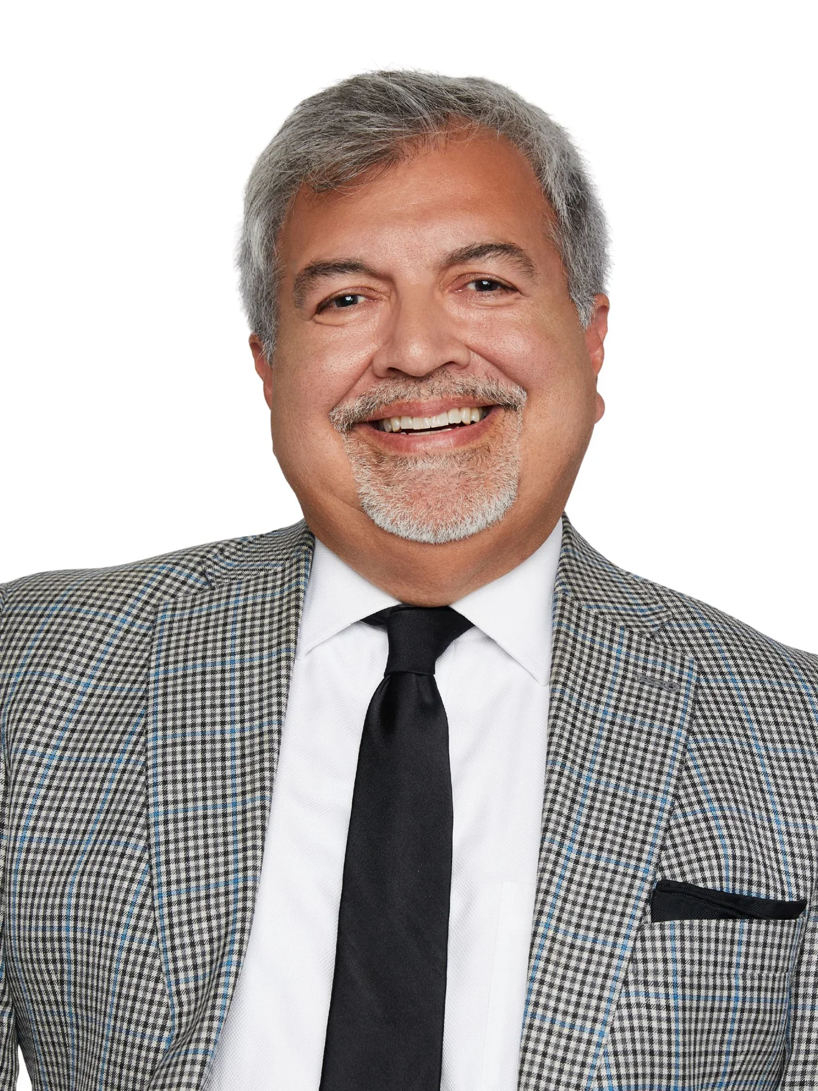 A smiling middle-aged man with gray hair, gray beard, wearing a checkered blazer, white shirt, and black tie.