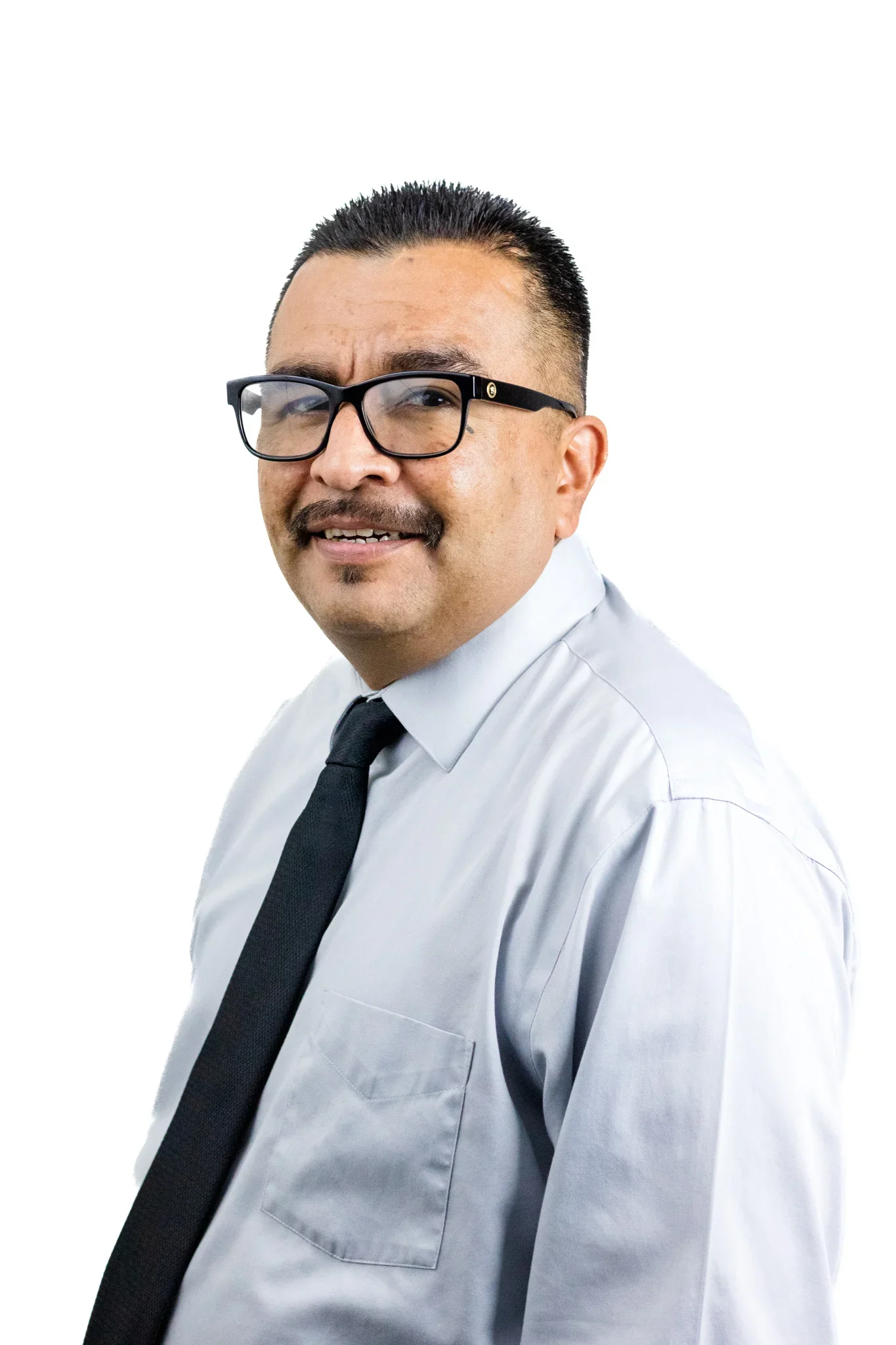 Headshot of a man with short black hair, glasses, mustache, and goatee, smiling, wearing a white shirt and black tie, against a plain white background.